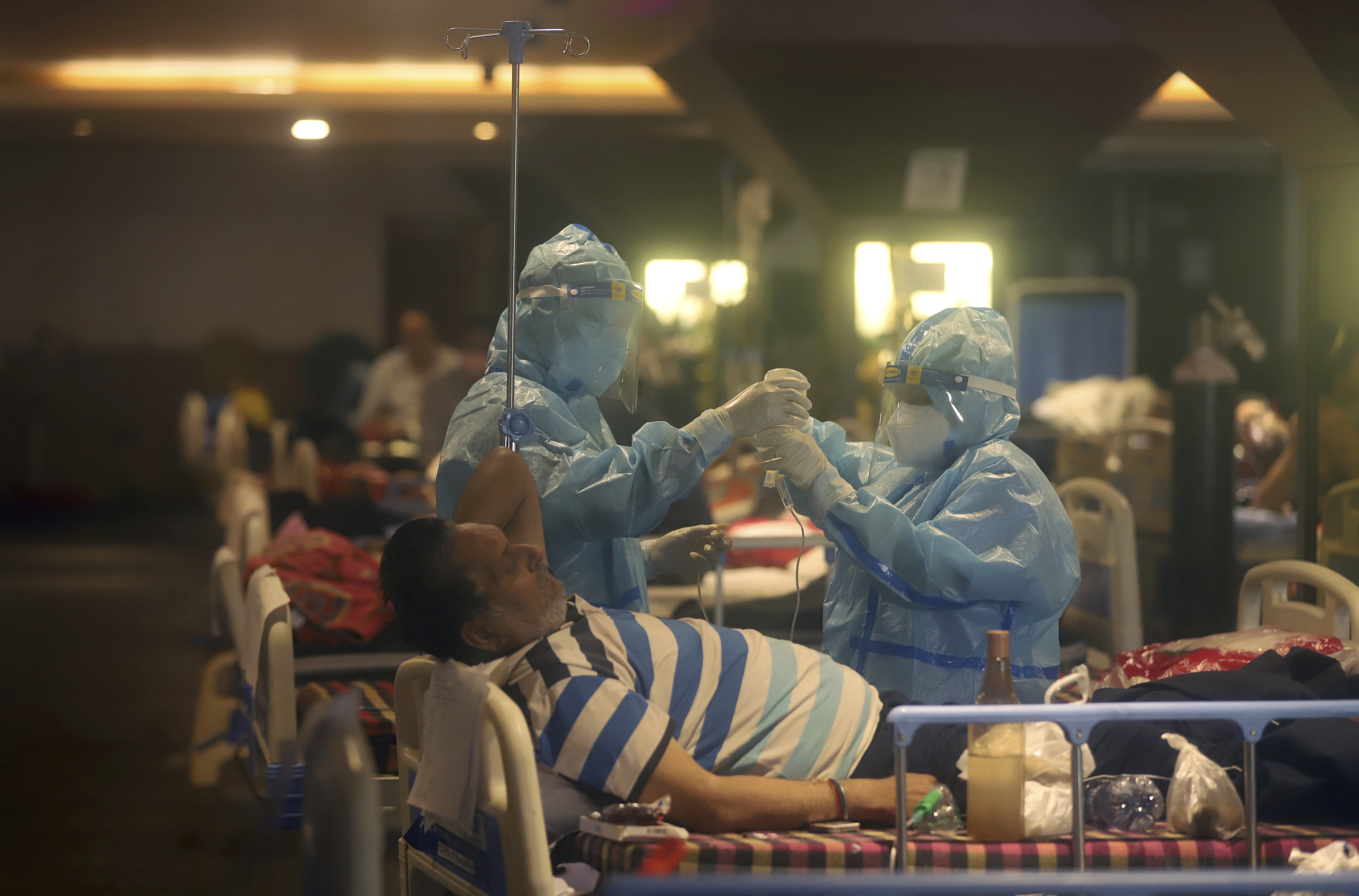 Health workers attend to COVID-19 patients at a makeshift hospital in New Delhi [File: AP Photo]