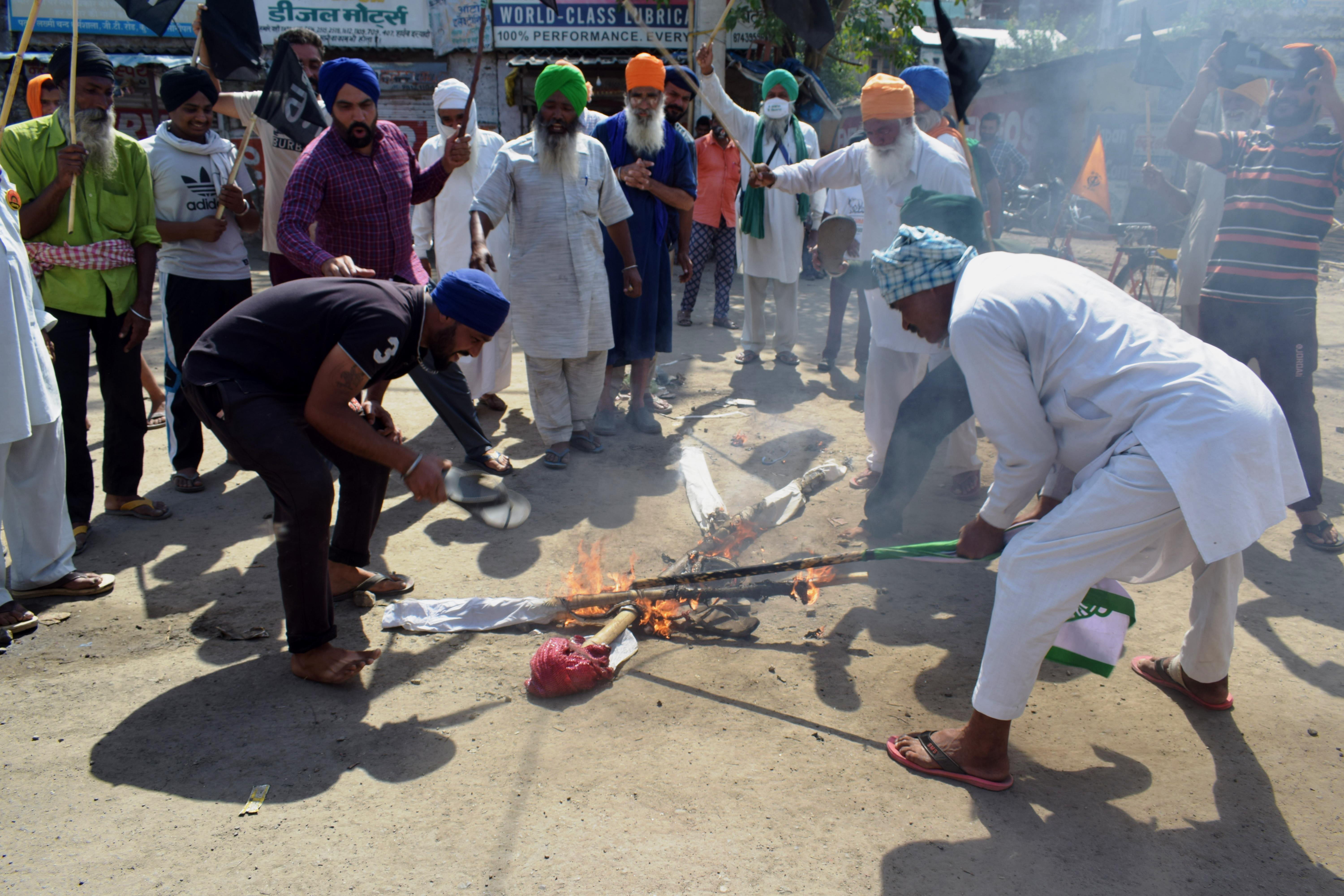Farmers raising slogans against Prime Minister Narendra Modi while burning his effigy, on the outskirts of New Delhi [Hasan Akram/Al Jazeera]