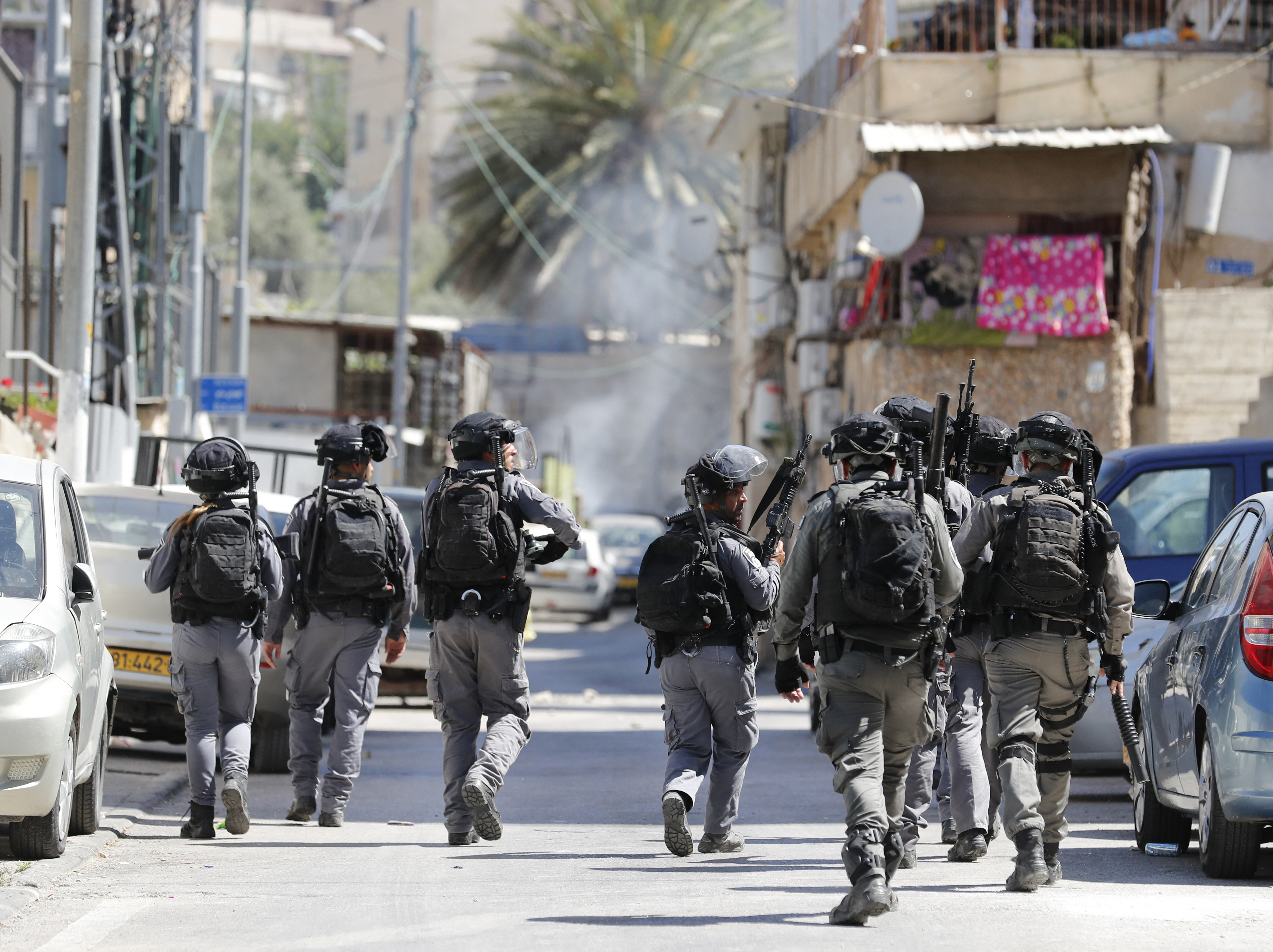 Israeli soldiers walk through a narrow street