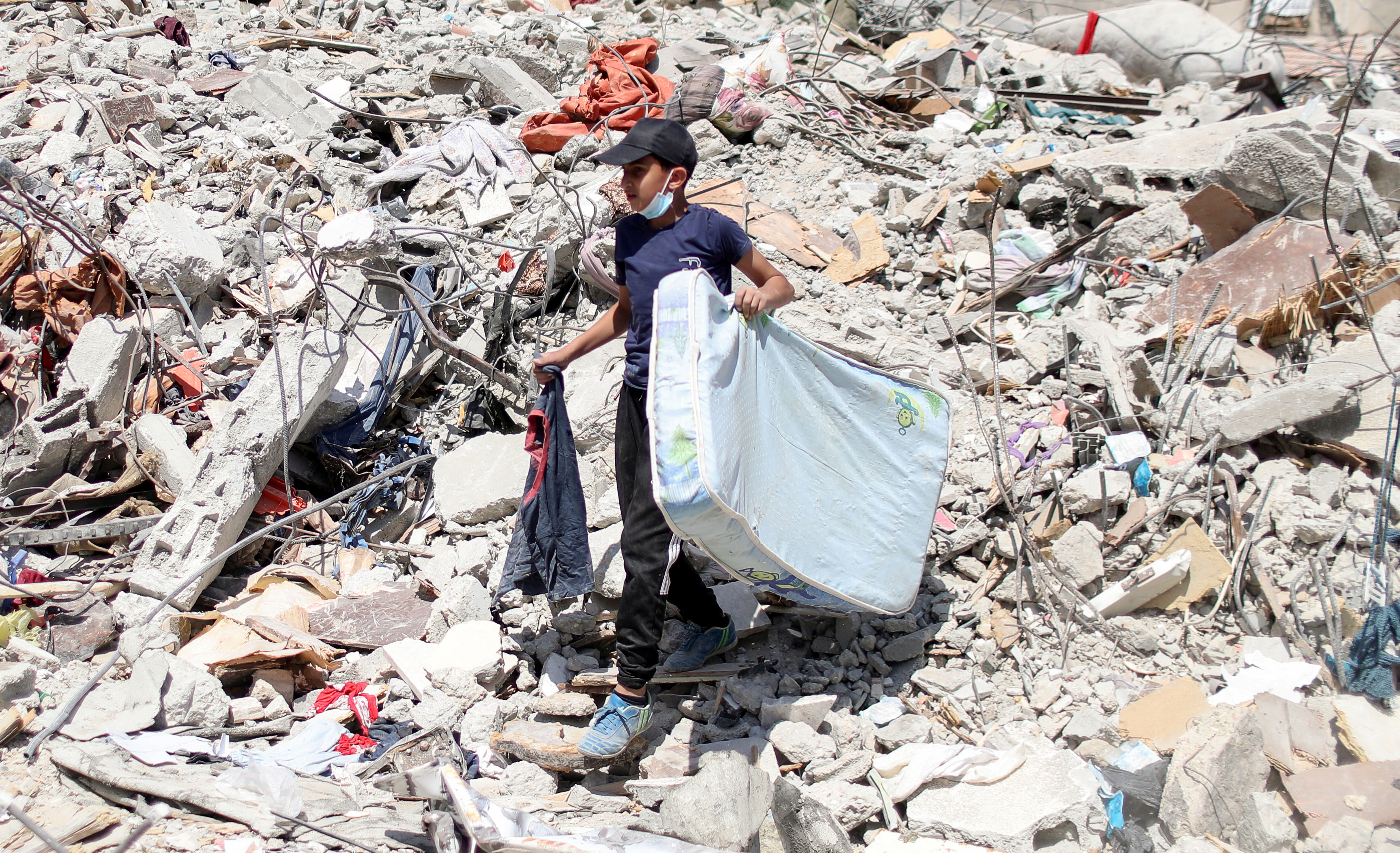 A Palestinian boy walks through the debris of a house destroyed in Israeli air raids on Gaza City [Mohammed Salem/Reuters]