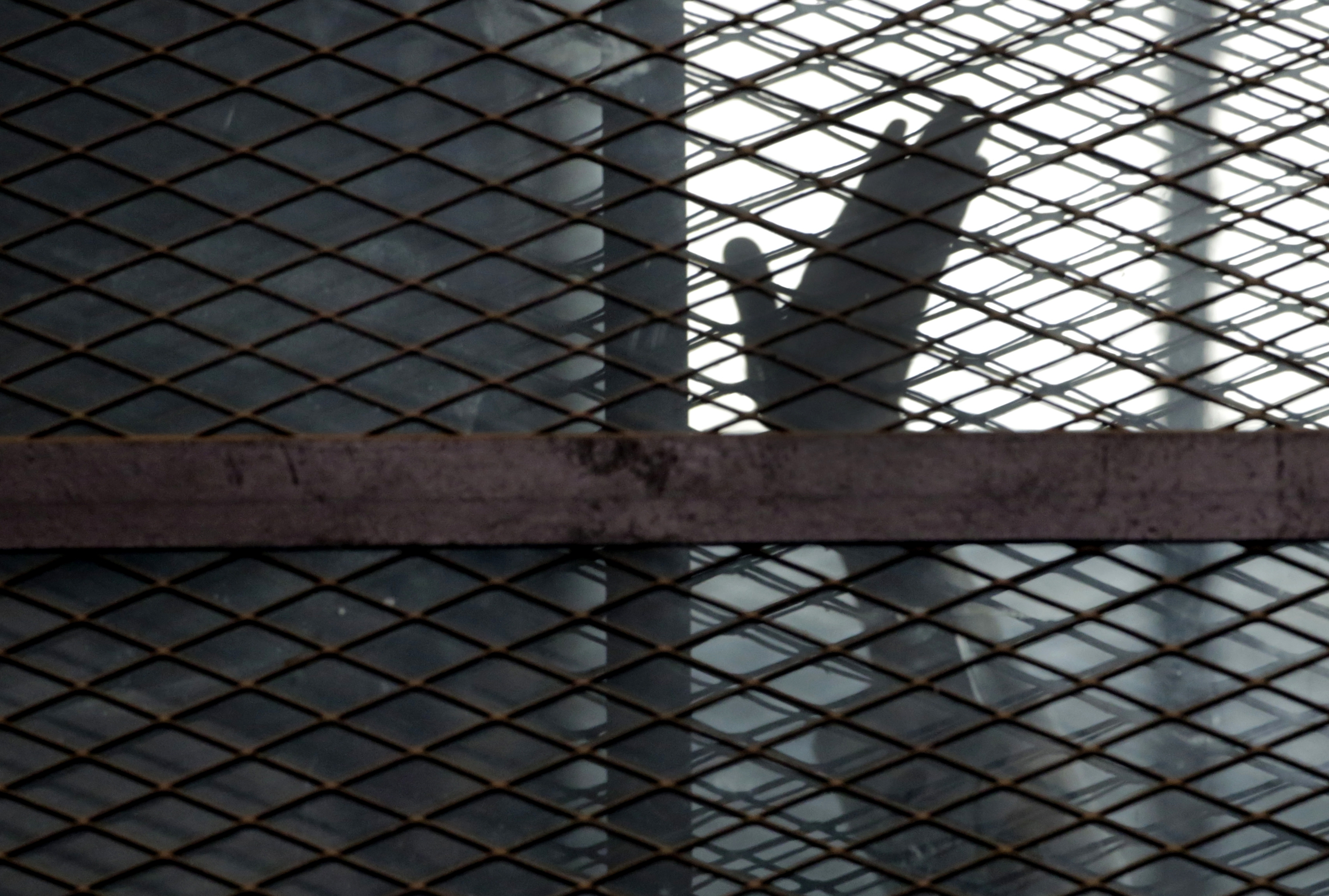 A member of the Muslim Brotherhood waves his hand from a defendant's cage in a courtroom in Torah prison, southern Cairo, Egypt [File: Amr Nabil/AP Photo]