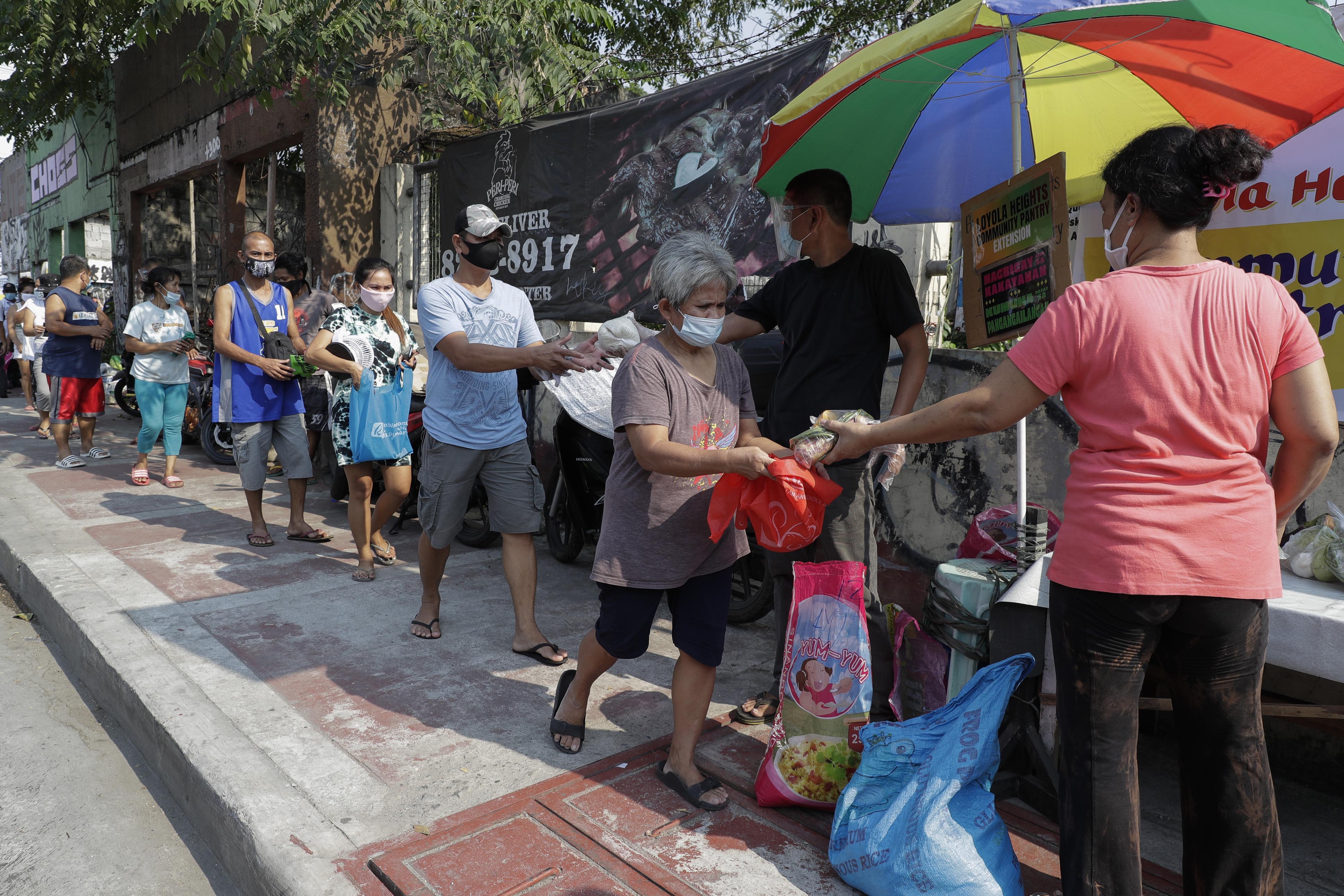 Residents receive free food at a 'community pantry'. The pantries have been popping up across the capital to help people cope during the government lockdown to curb the spread of the coronavirus in Quezon City, Philippines on April 29, 2021 [File: Aaron Favila/AP]