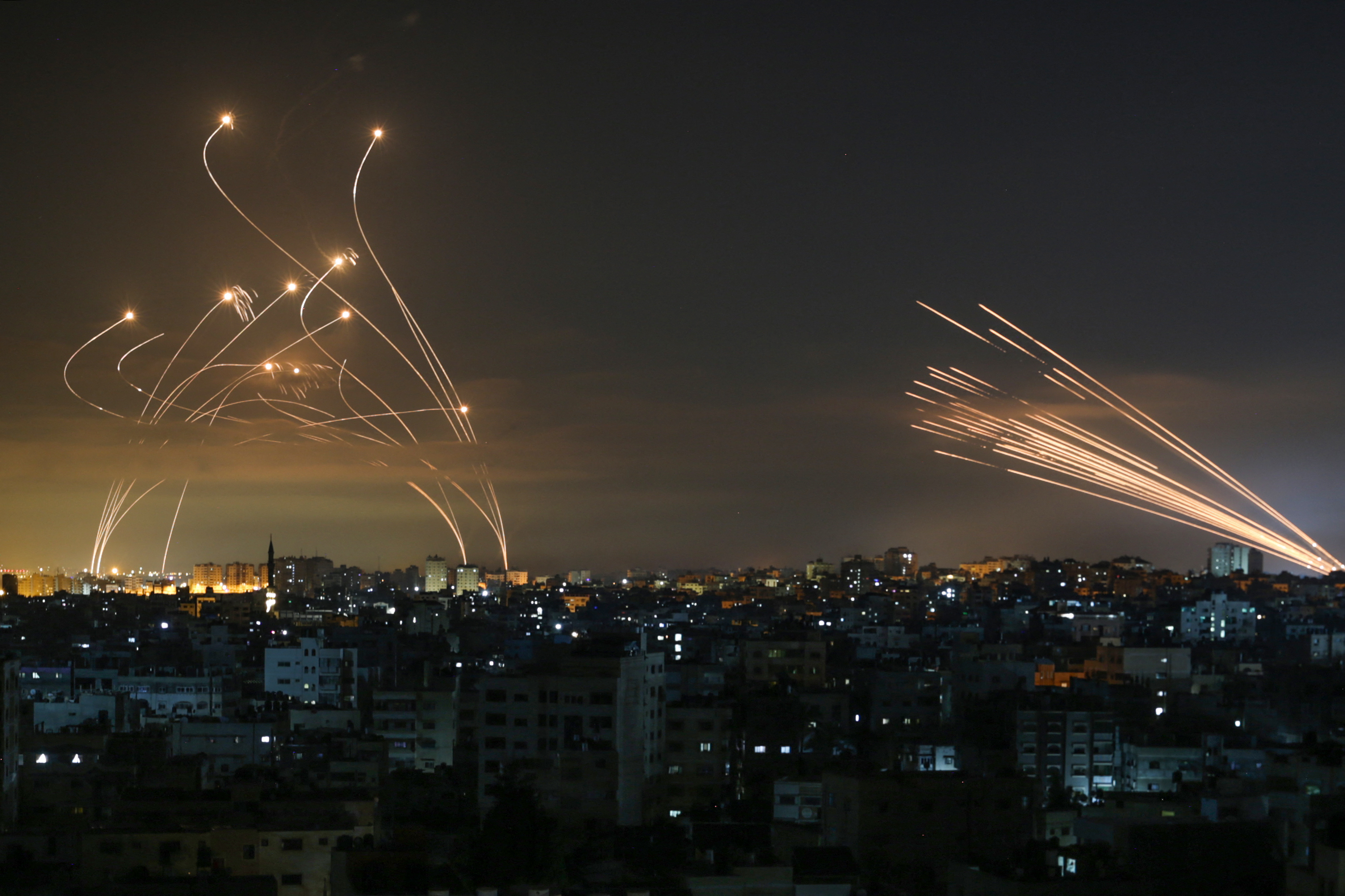 The Israeli Iron Dome missile defence system (L) intercepts rockets (R) fired by the Hamas movement towards southern Israel from Beit Lahia in the northern Gaza Strip as seen in the sky above the Gaza Strip overnight on May 14, 2021. - Israel bombarded Gaza with artillery and air strikes on Friday, May 14, in response to a new barrage of rocket fire from the Hamas-run enclave, but stopped short of a ground offensive in the conflict that has now claimed more than 100 Palestinian lives.