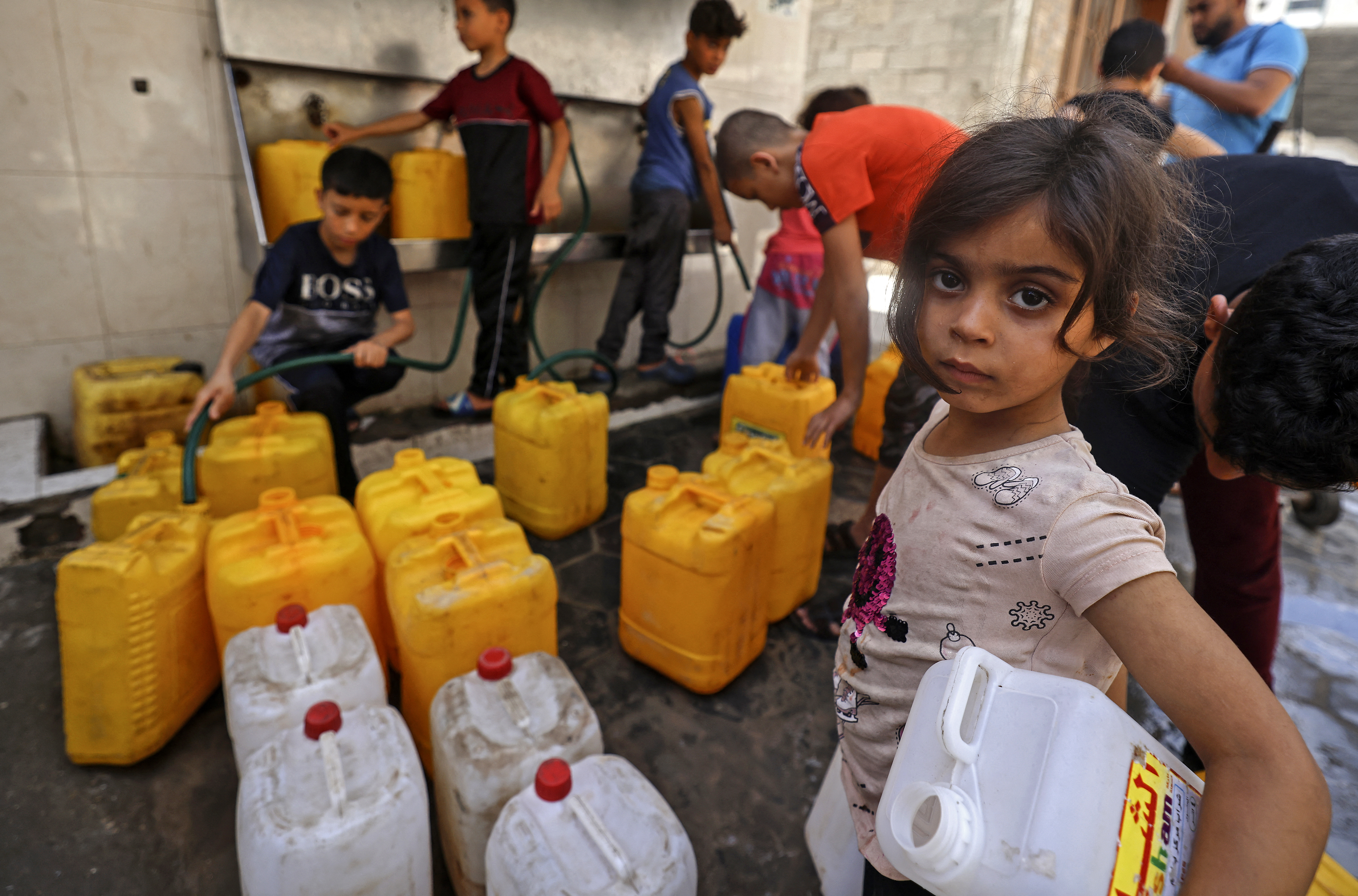 Palestinian children fill up gallons with water in Gaza City on May 20, 2021 [File: Mahmud Hams/AFP]