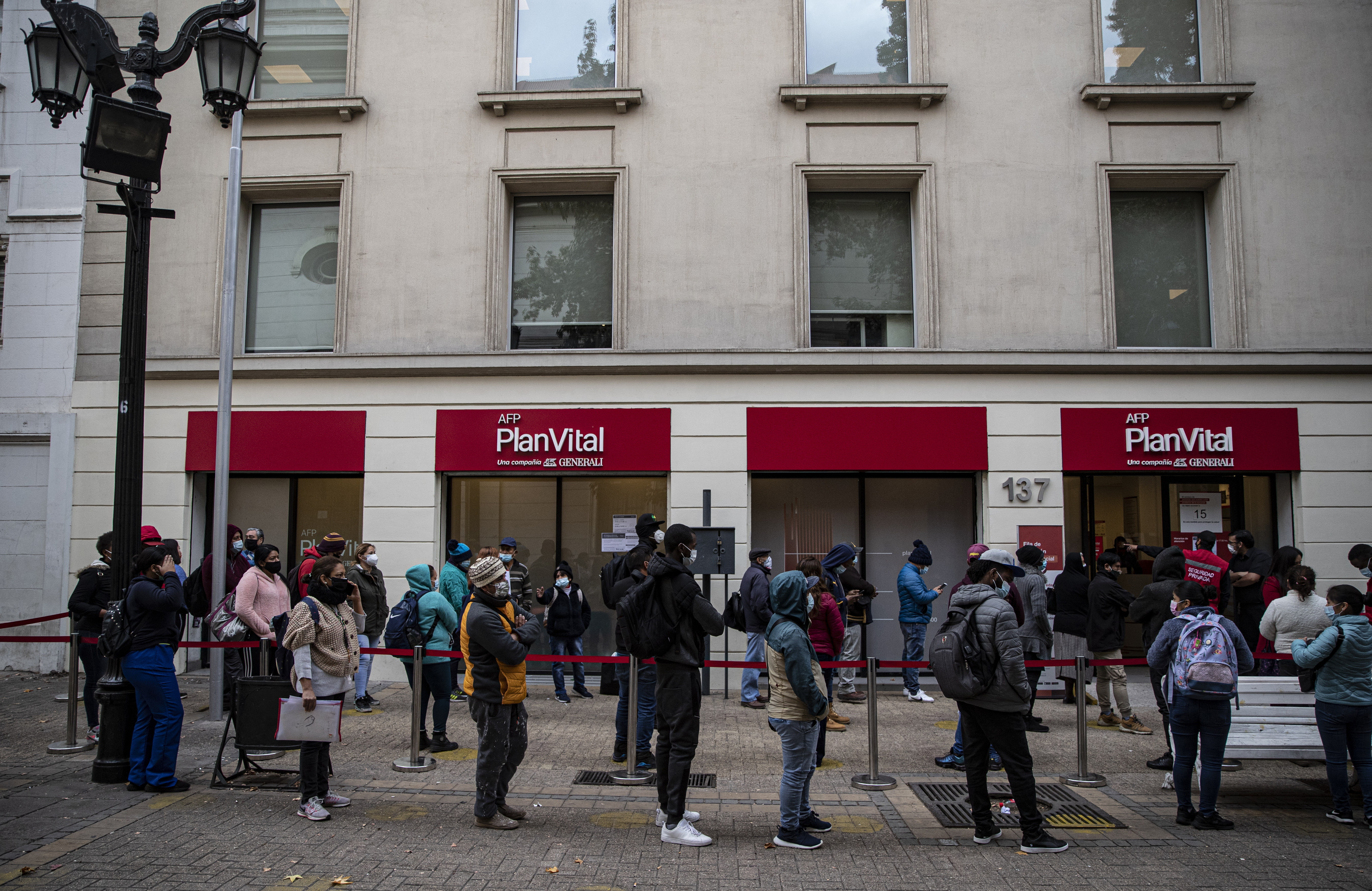 Chileans line up outside a pension administration office to apply for an early withdrawal of a percentage of their pensions to help them ride out the coronavirus recession in downtown Santiago, Chile, on May 3 [File: Esteban Felix/AP Photo]