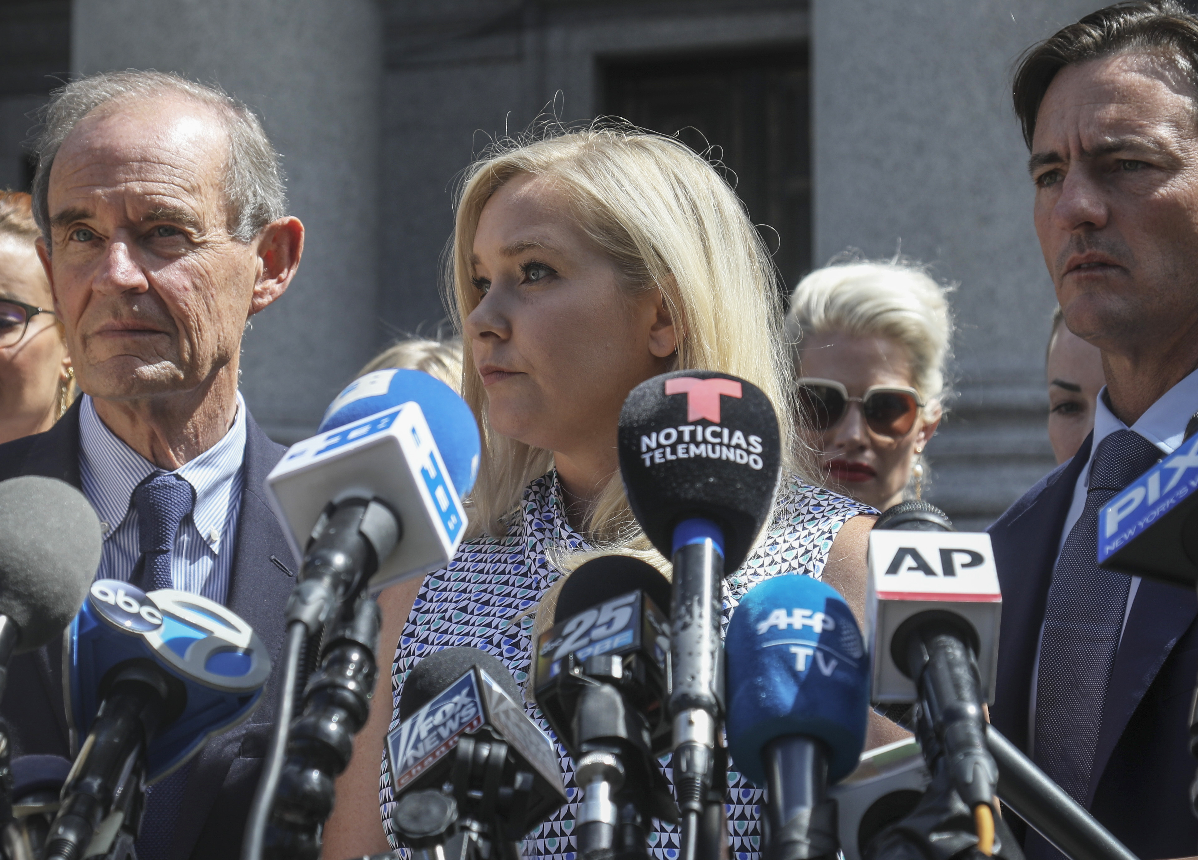 Virginia Roberts Giuffre stands in front of a bank of microphones as she speaks to the press