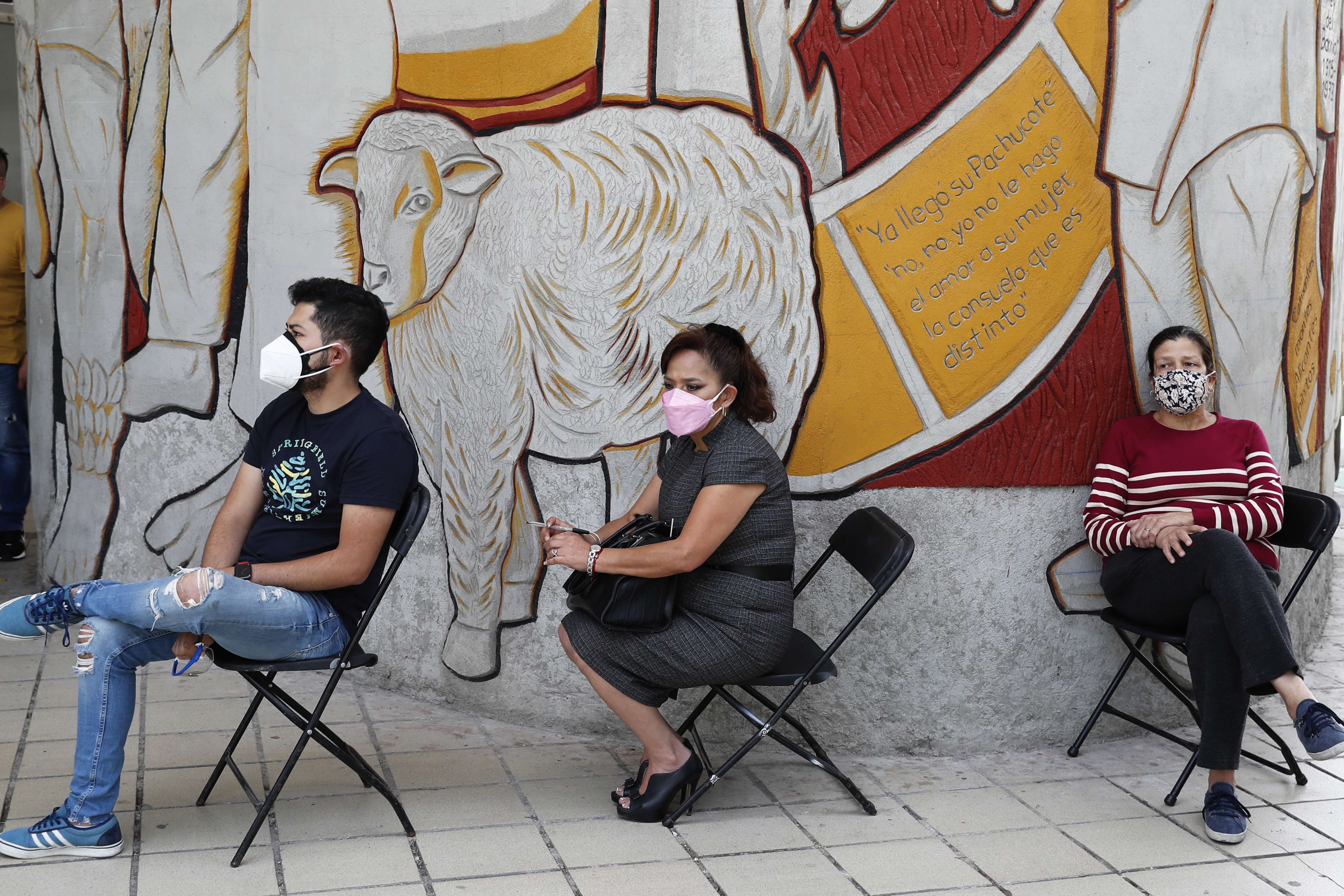 Three people are sitting in chairs waiting to be tested for COVID-19 in Mexico City