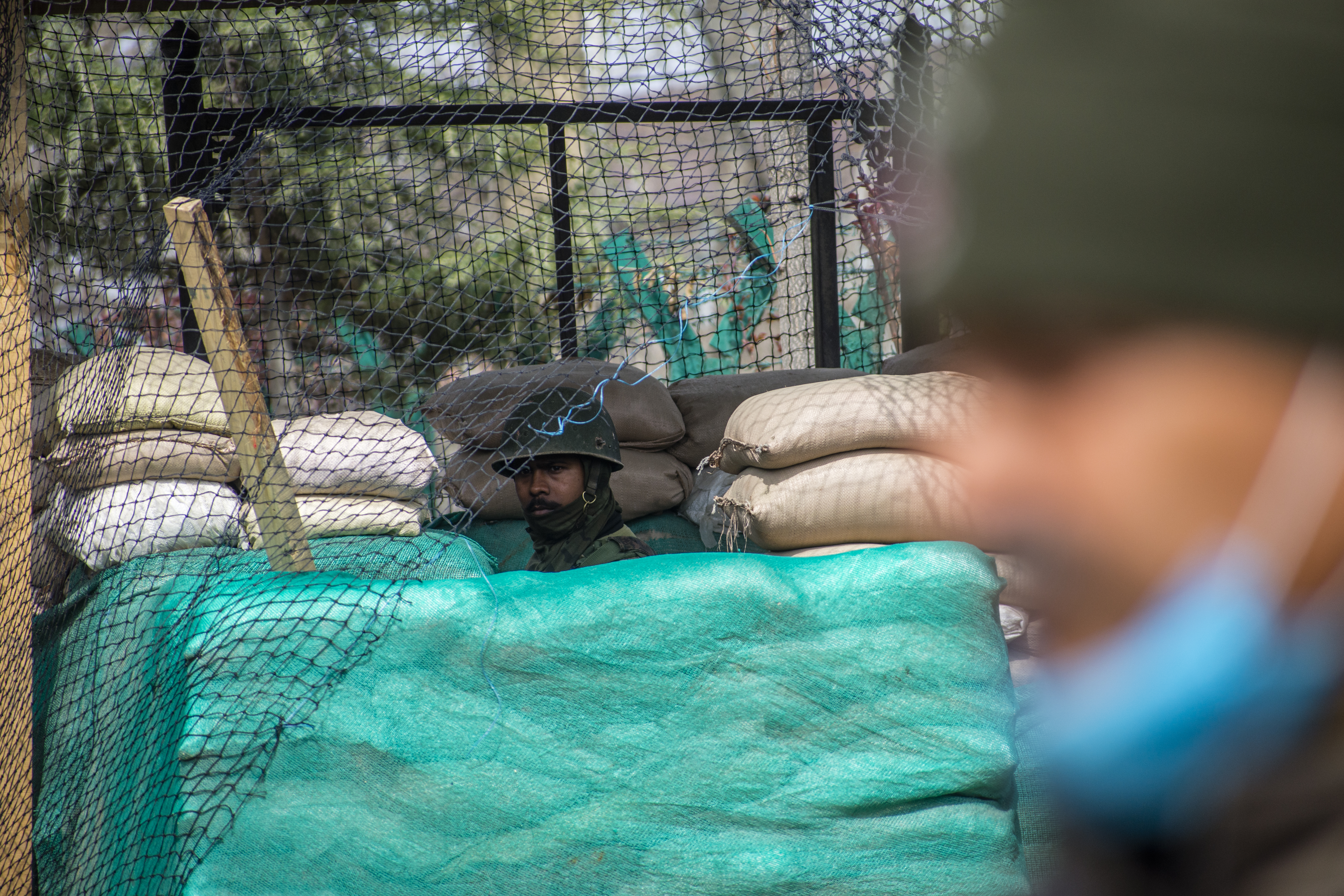 An Indian paramilitary soldier stands alert in his bunker on a road, on March 15, 2021 in Srinagar, Indian-administered Kashmir, India. [Yawar Nazir/Getty Images]