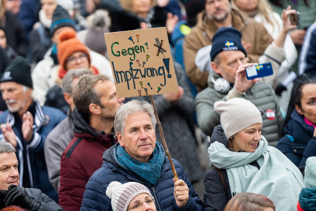 A demonstrator holds a placard reading 'Against compulsory vaccination'