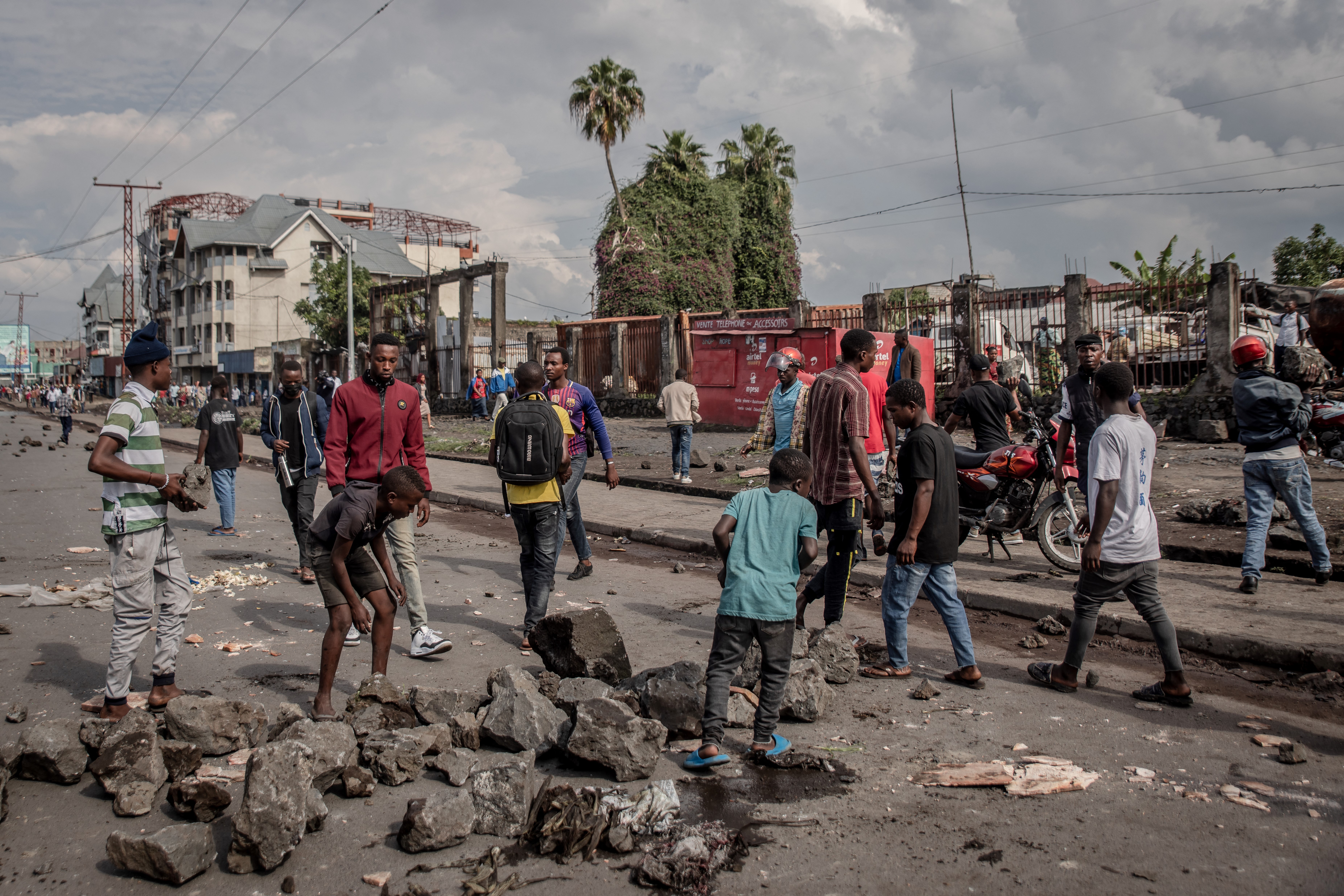 People remove stones from a street while police disperse people barricading roads in Goma, eastern Democratic Republic of Congo, on December 20, 2021.