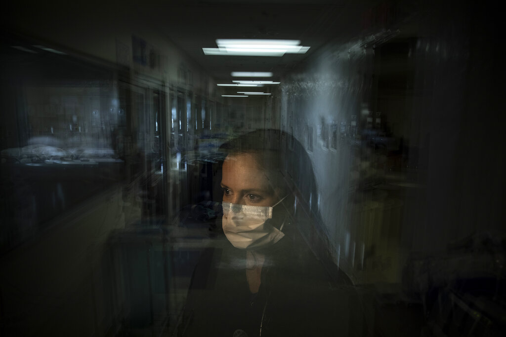 A masked woman is viewed through a pane of glass.