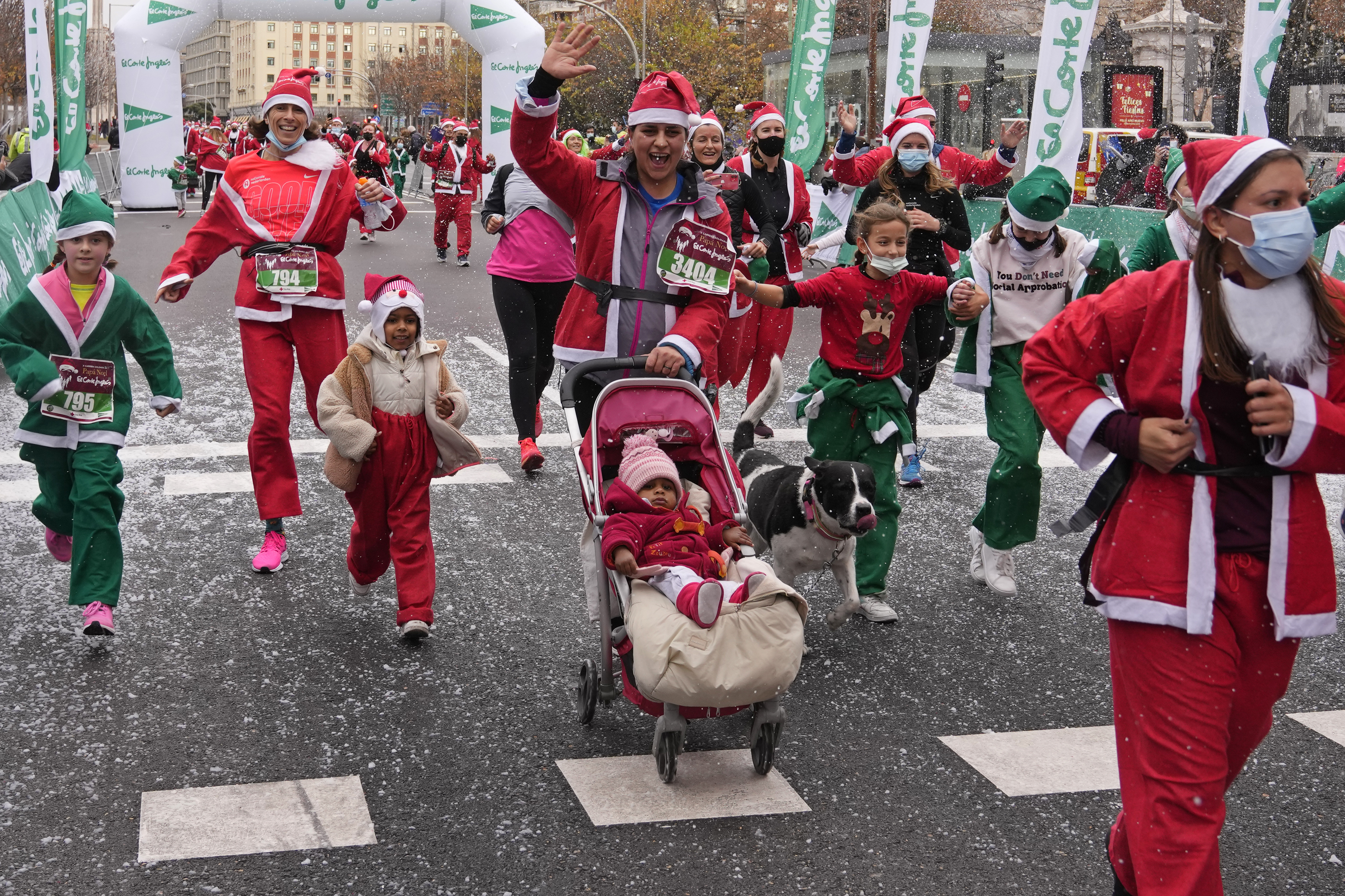 People dressed in Santa Claus costumes cross the finish line during a morning run in Madrid, on December 19, 2021 [AP/Paul White]