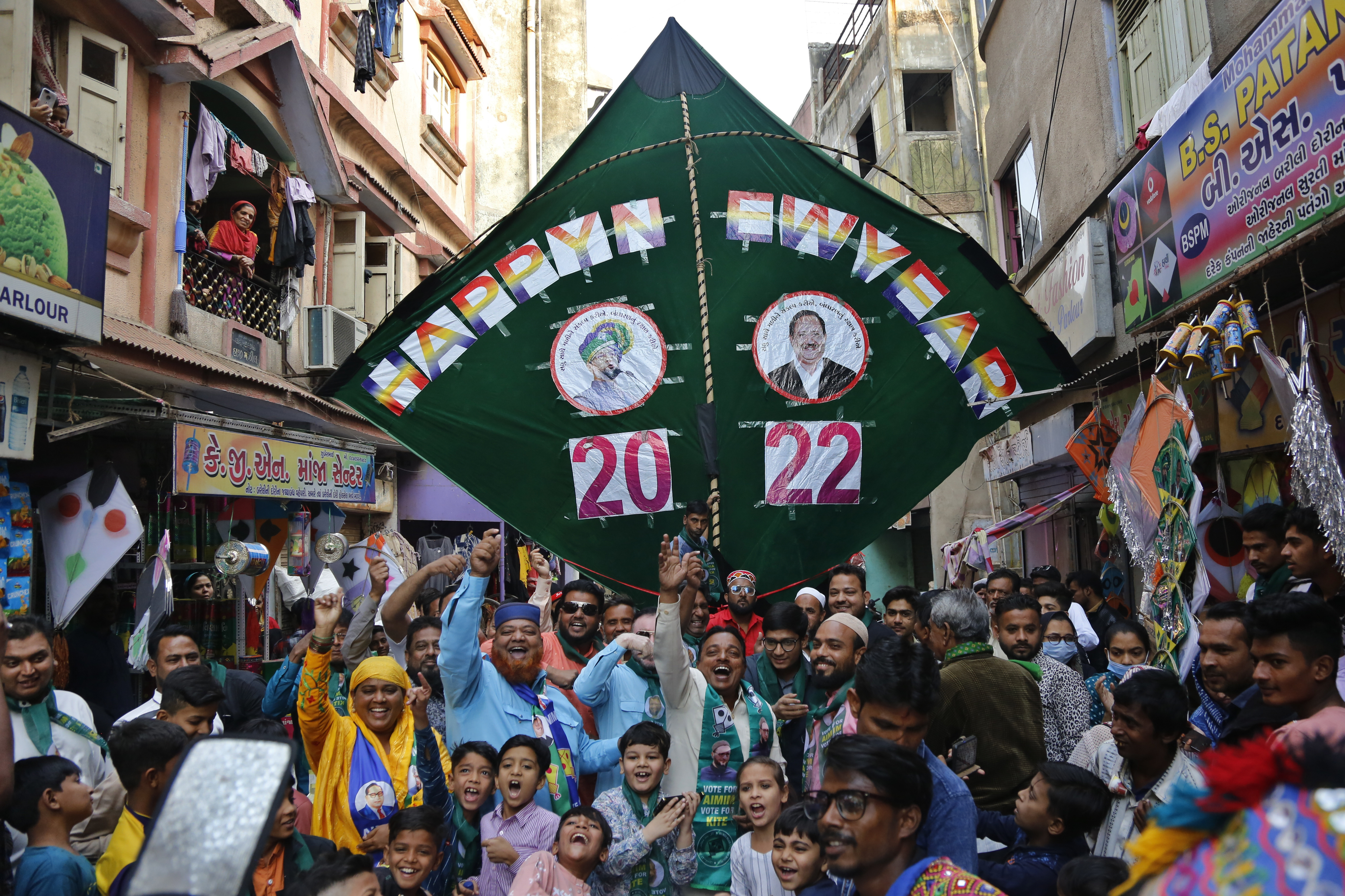 Workers of a political party and others cheer in front of a huge kite on a public street to welcome 2022 on New Year’s Eve in Ahmedabad, India