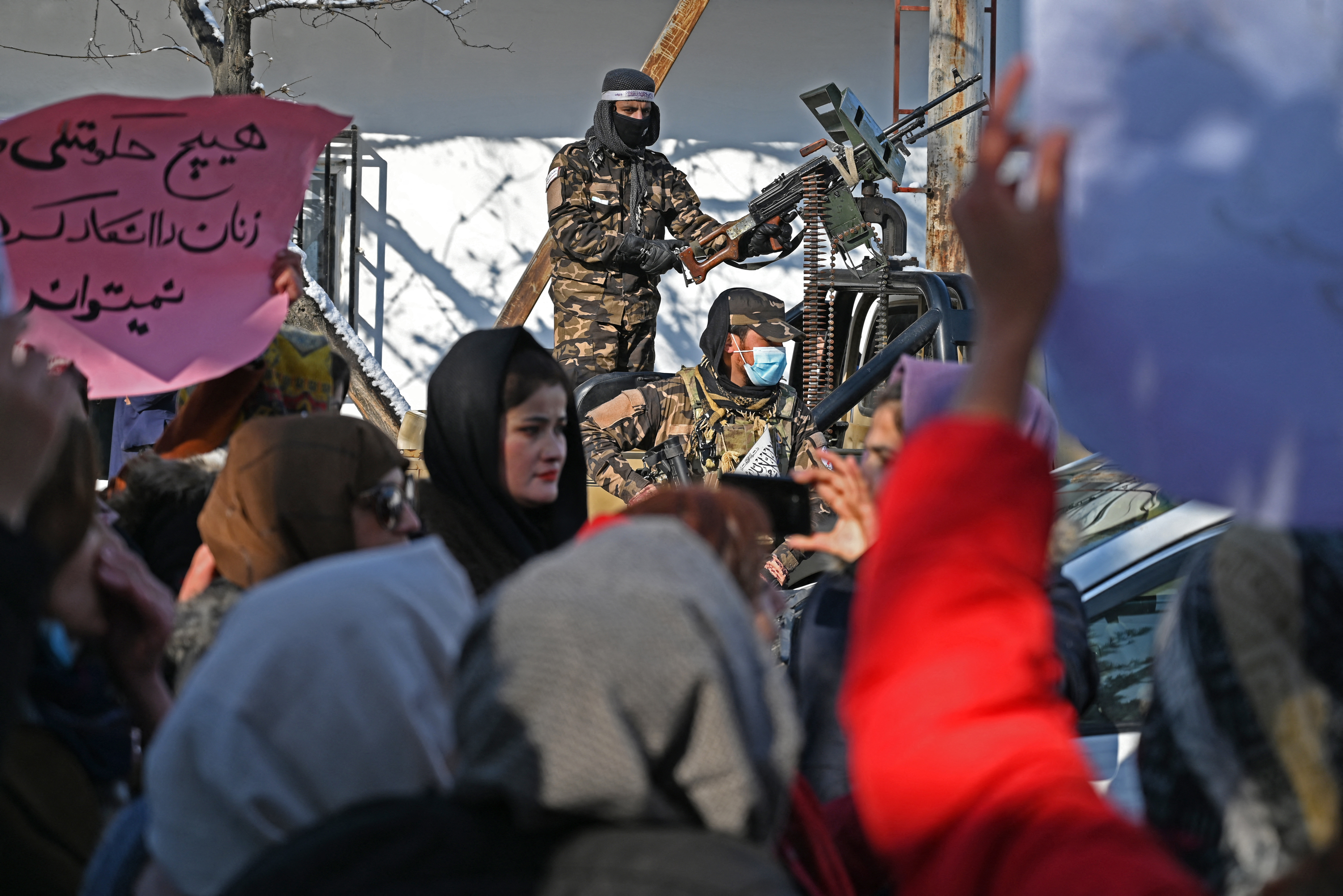 Taliban fighters stand guard on a vehicle as Afghan women protest 