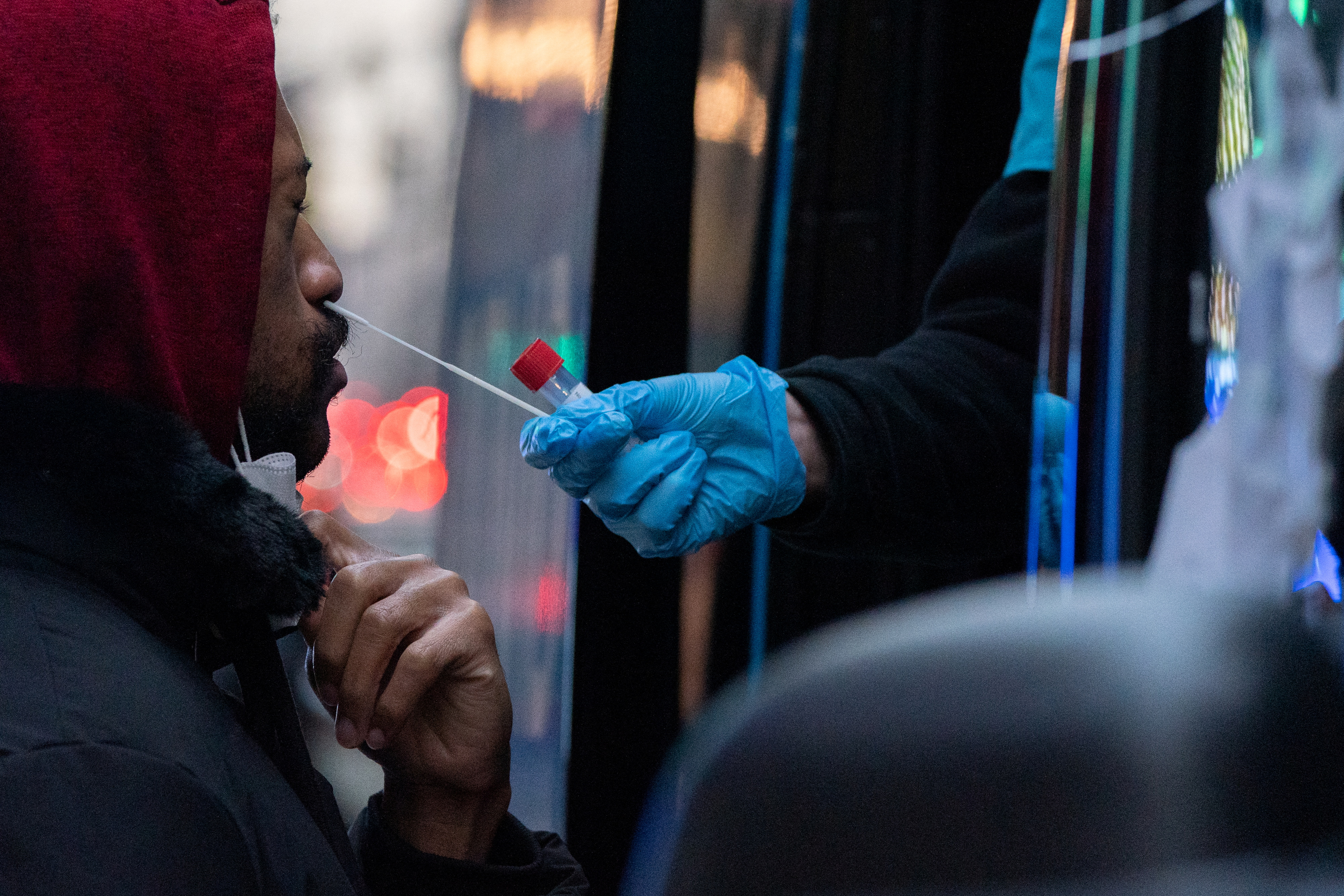 A man with his eyes shut as a medical worker swabs his nose while testing him for COVID-19.