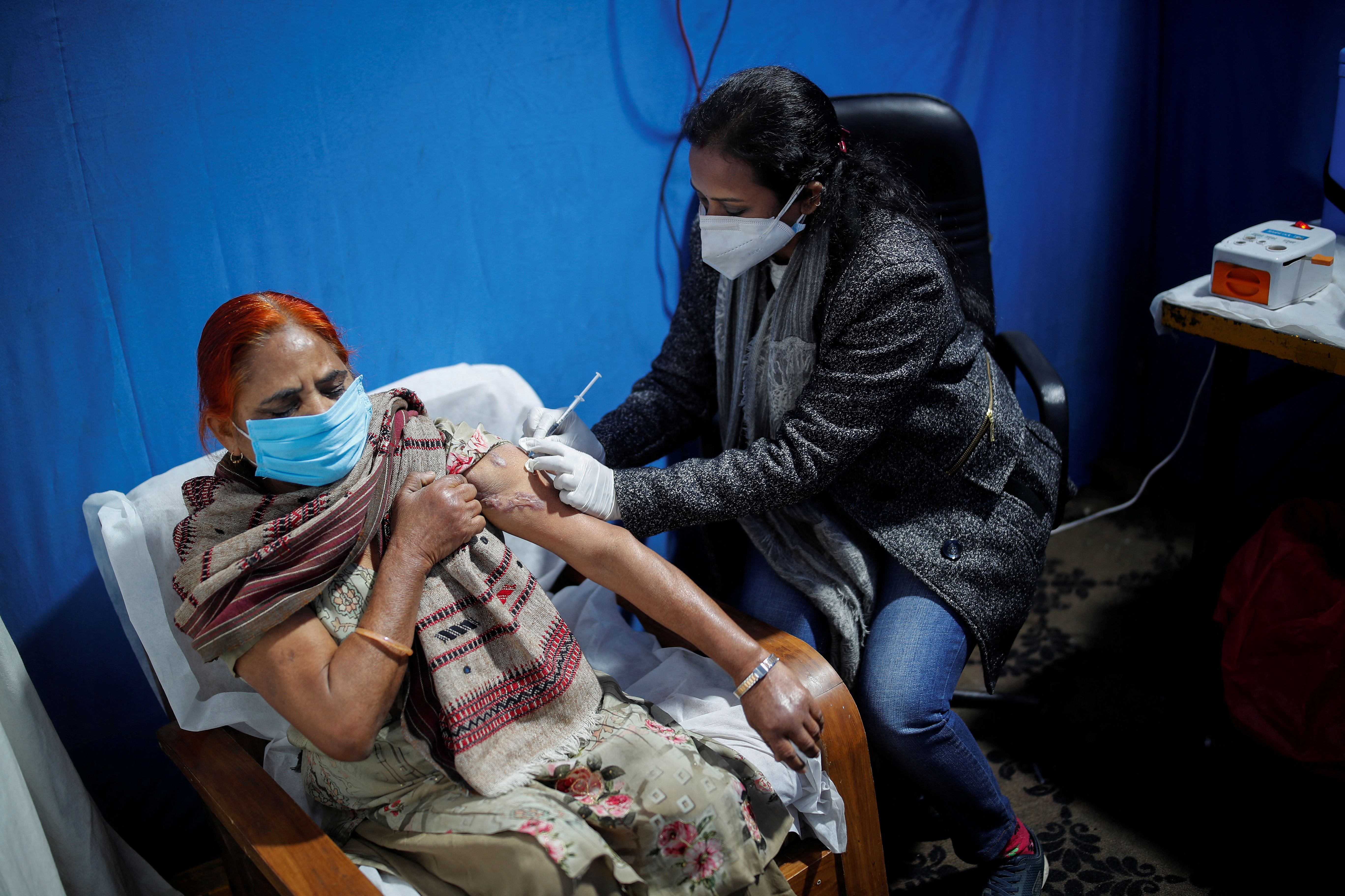 A woman receives a booster at a vaccination centre in New Delhi, India