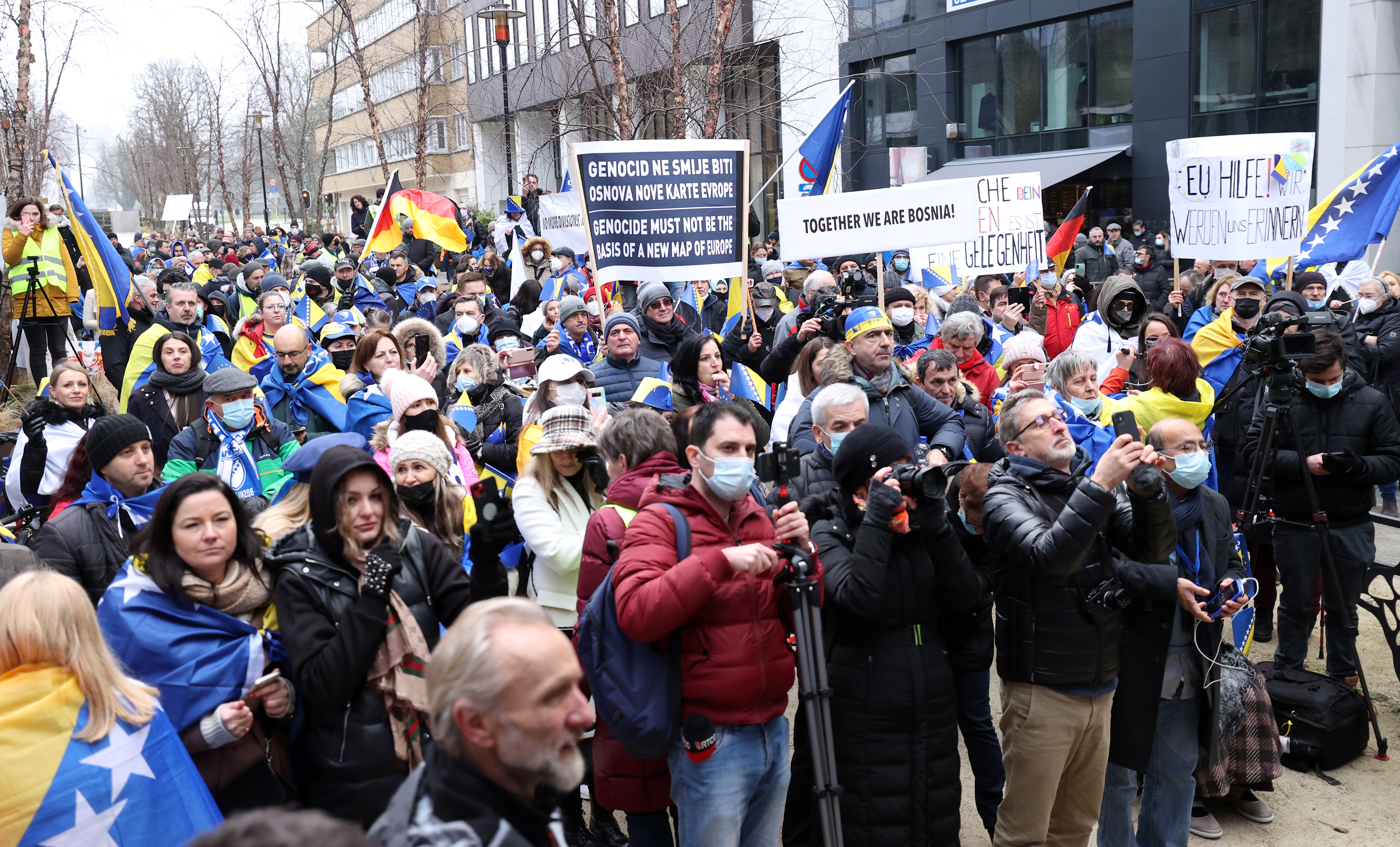 A crowd of protesters holding up signs and the national flag of Bosnia are seen outside in Brussels, Belgium