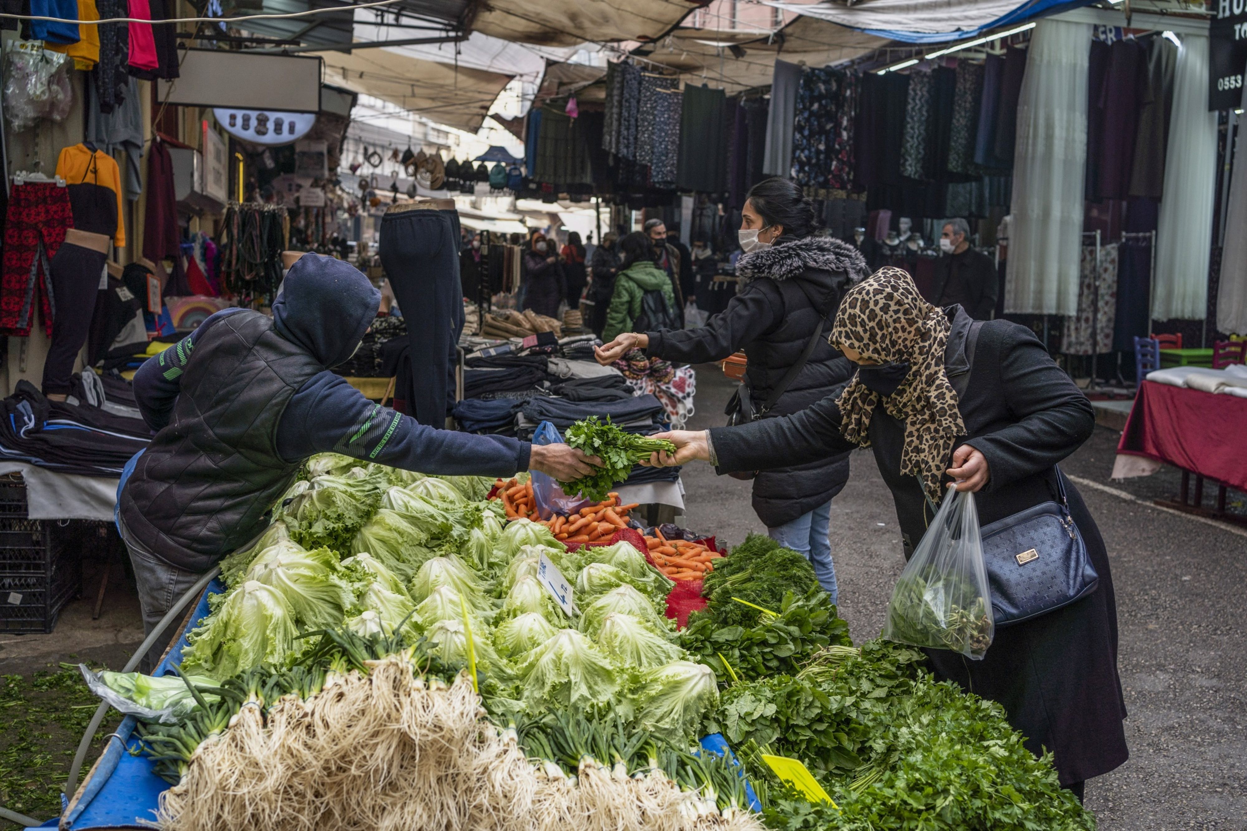 A customer purchases fresh herbs from a stall at a market in Bursa, Turkey