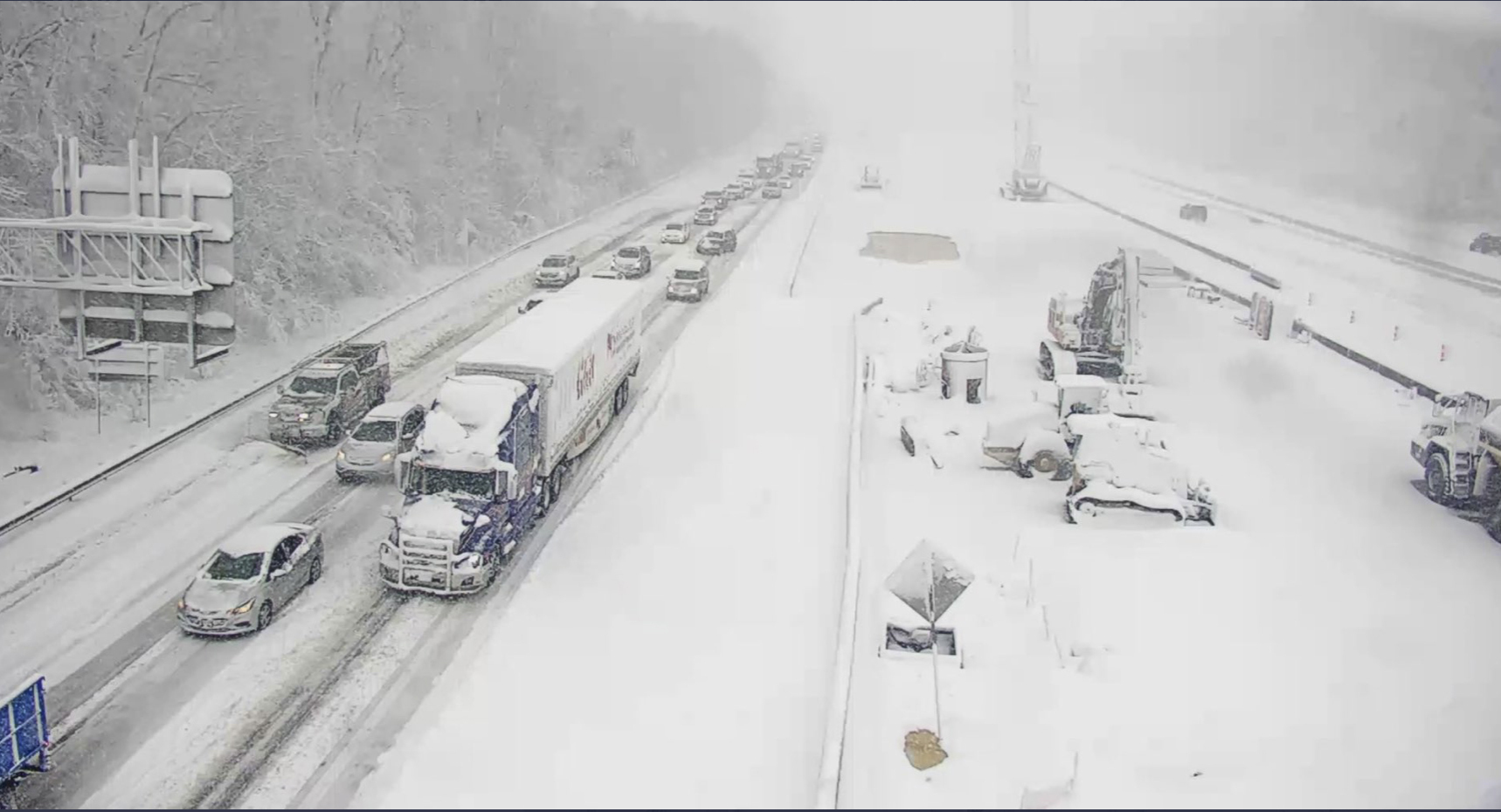 cars and trucks along I-95 at a standstill on snowy roadway
