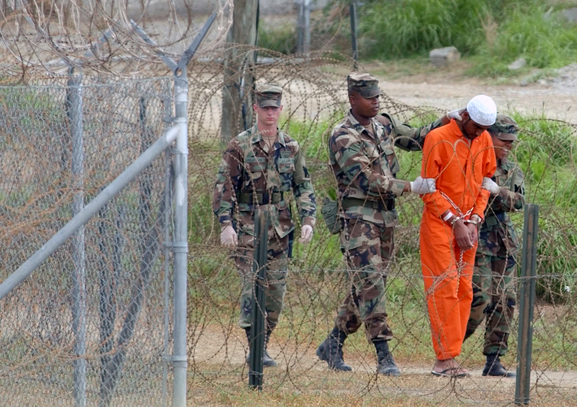 In this Feb. 6, 2002, file photo a detainee is led by military police to be interrogated by military officials at Camp X-Ray at the U.S. Naval Base at Guantanamo Bay, Cuba. At the time the image was taken there were 158 al-Qaida and Taliban