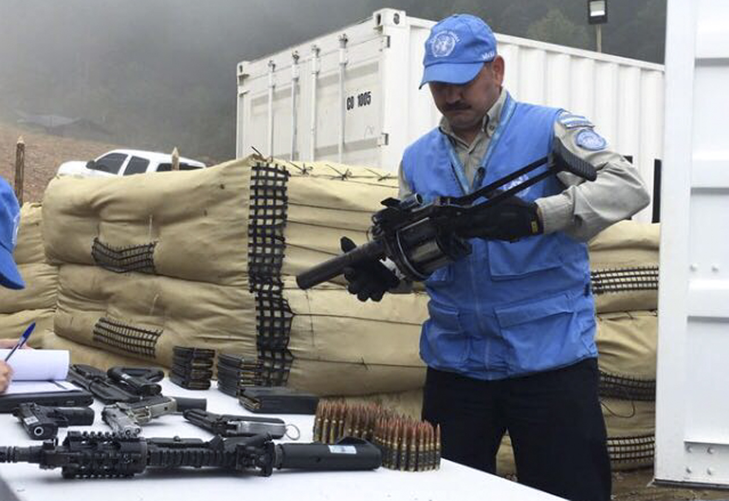 A UN worker holds a weapon handed over from former FARC rebels following 2016 peace agreement.