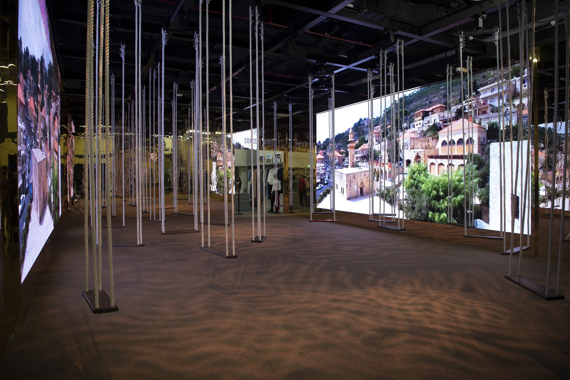 An installation with many swings is seen at the Lebanon Pavilion with a photo of Lebanon displayed on a large screen