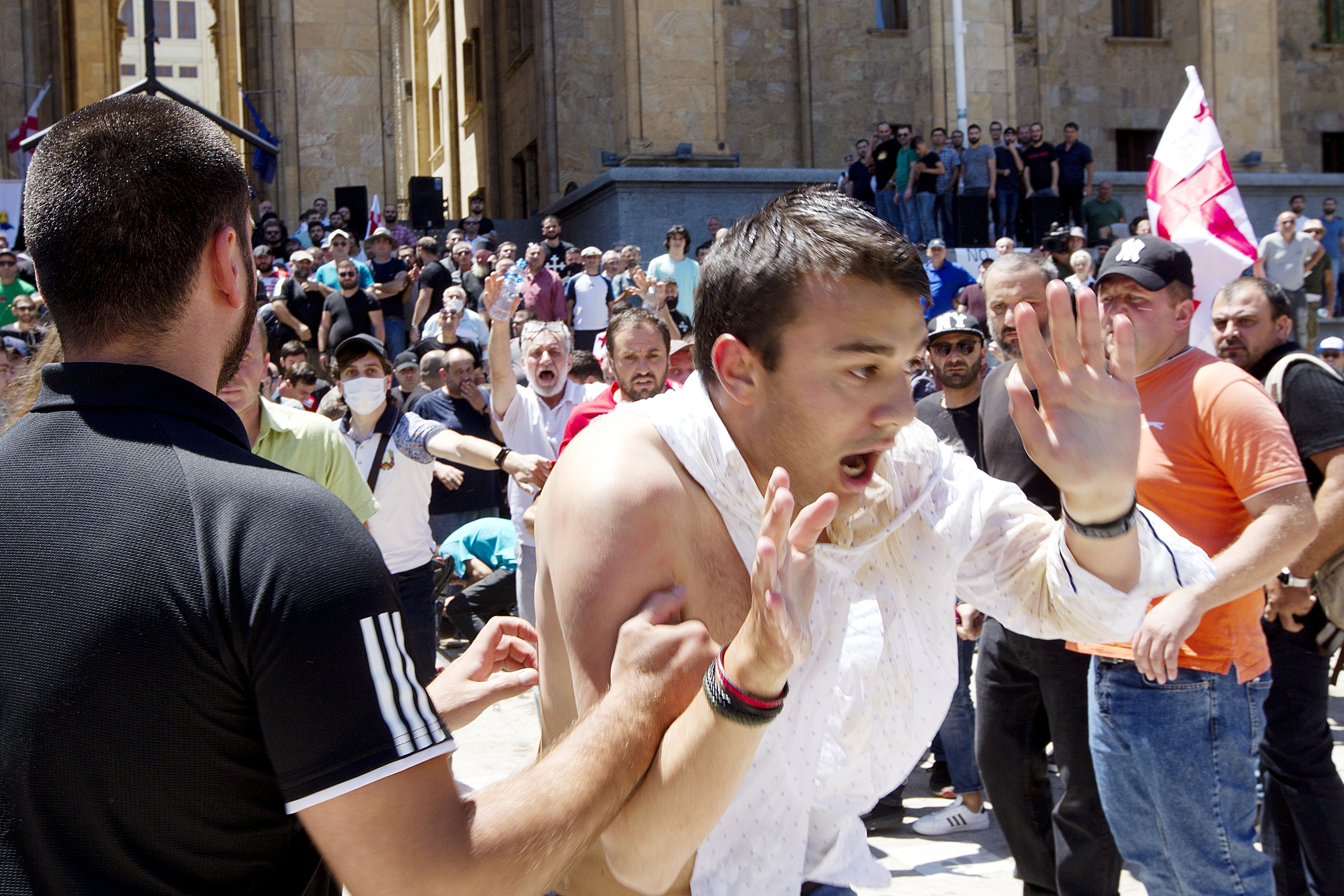 Opponents of the march push a man as they block off the capital's main avenue to an LGBT march in Tbilisi
