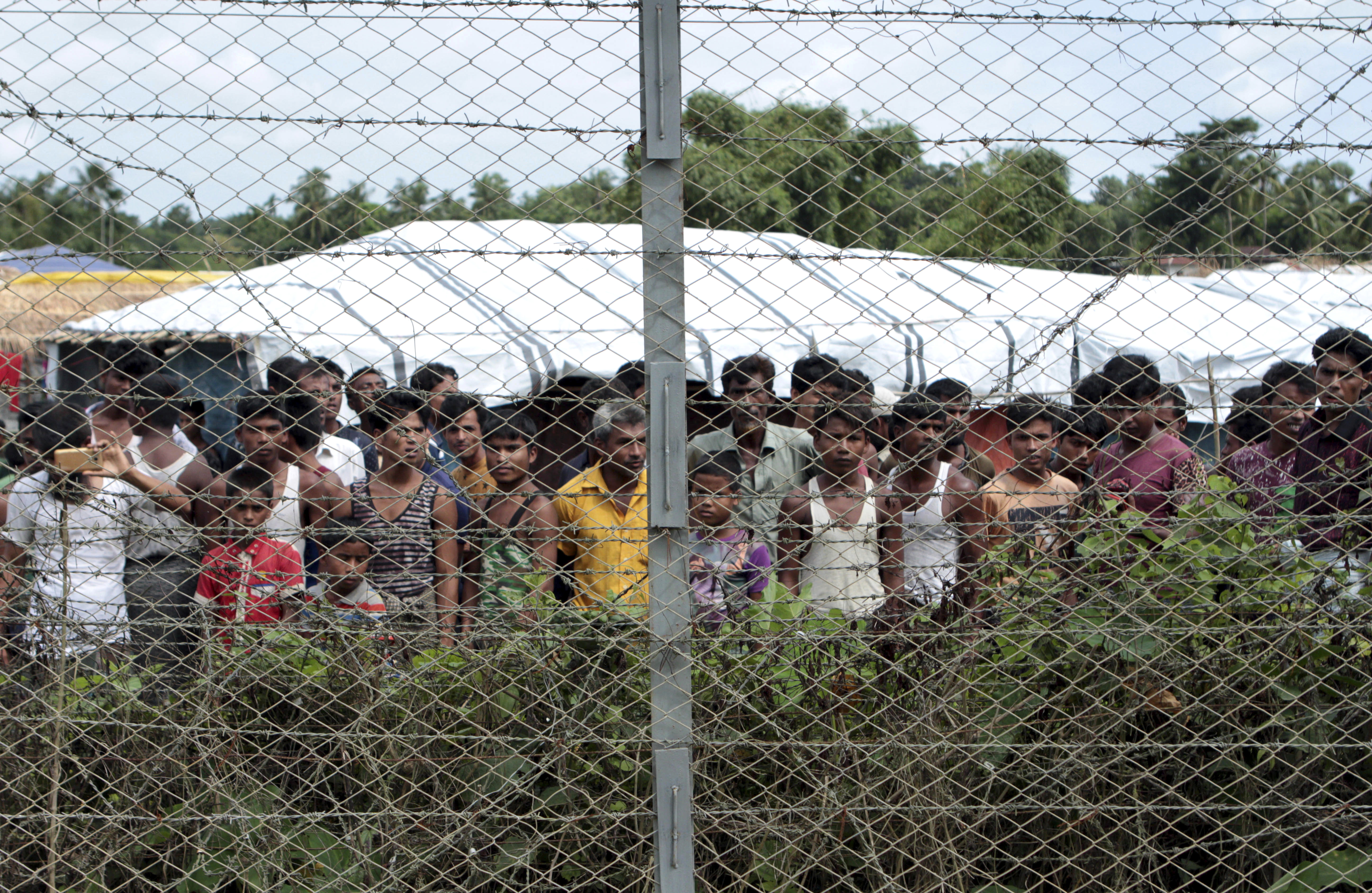 Rohingya men refugees are seen behind a fence