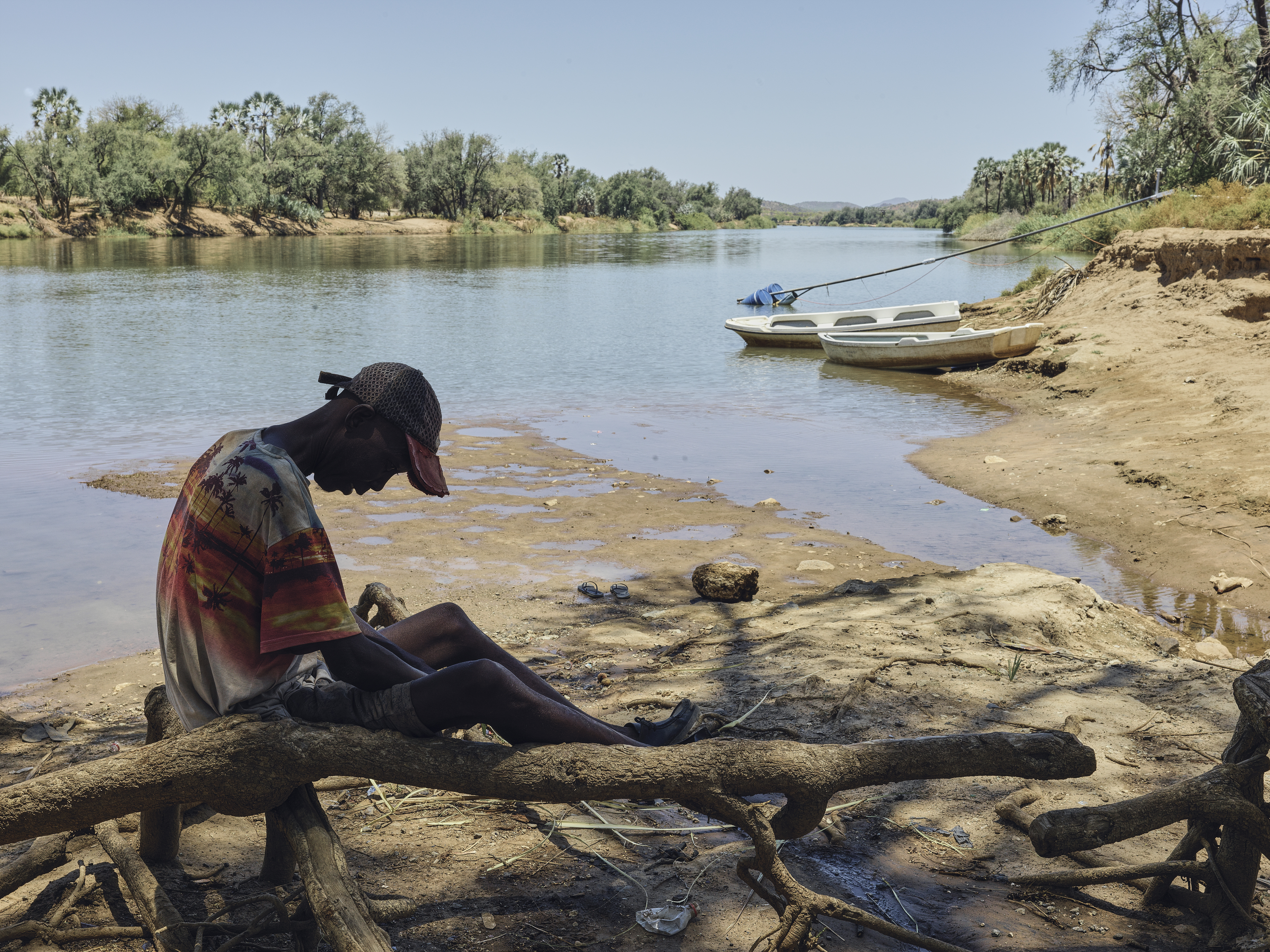 A photo of a man sitting by a river.