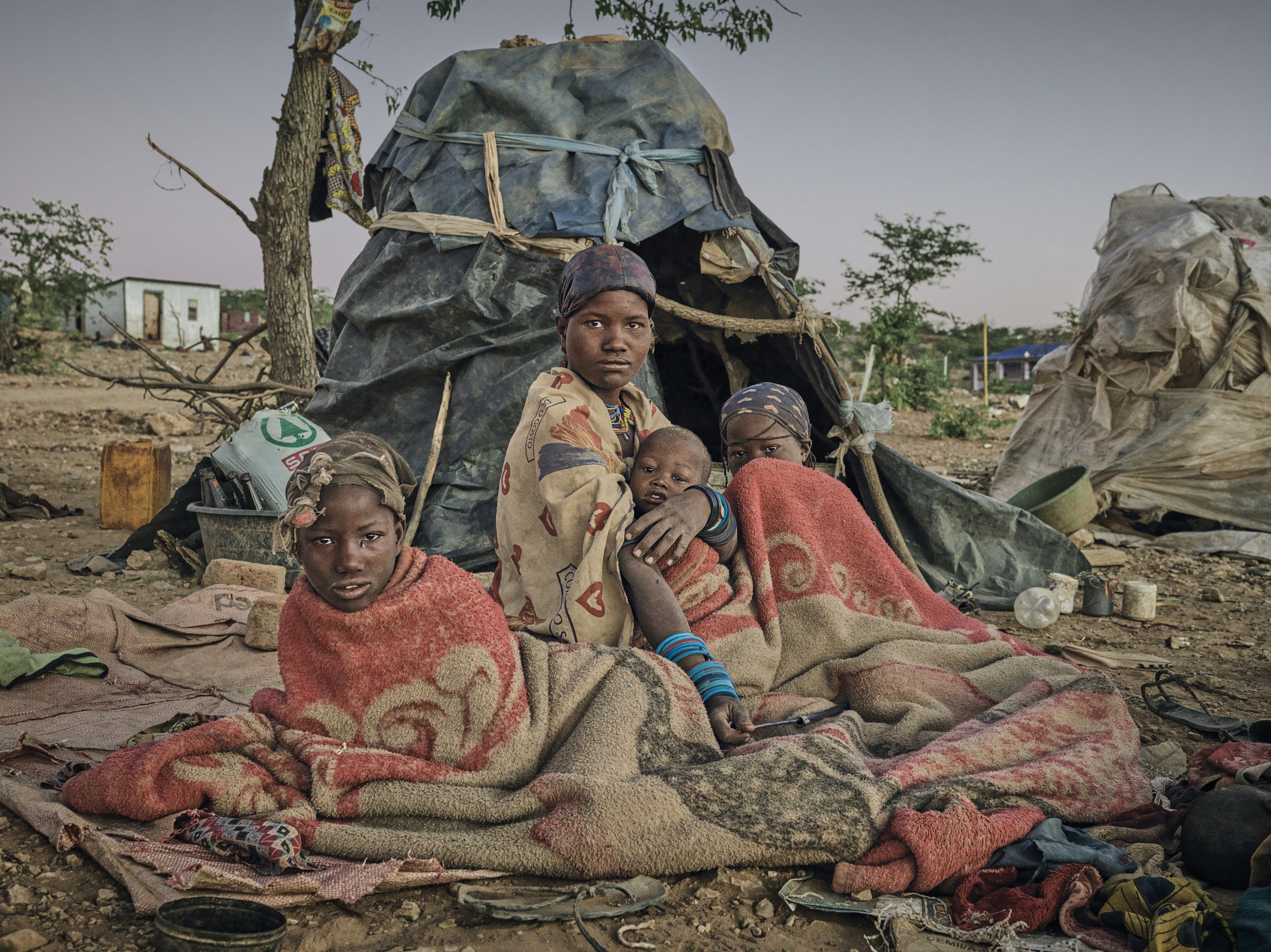 A photo of a woman and her family laying down on blankets outside a tent.