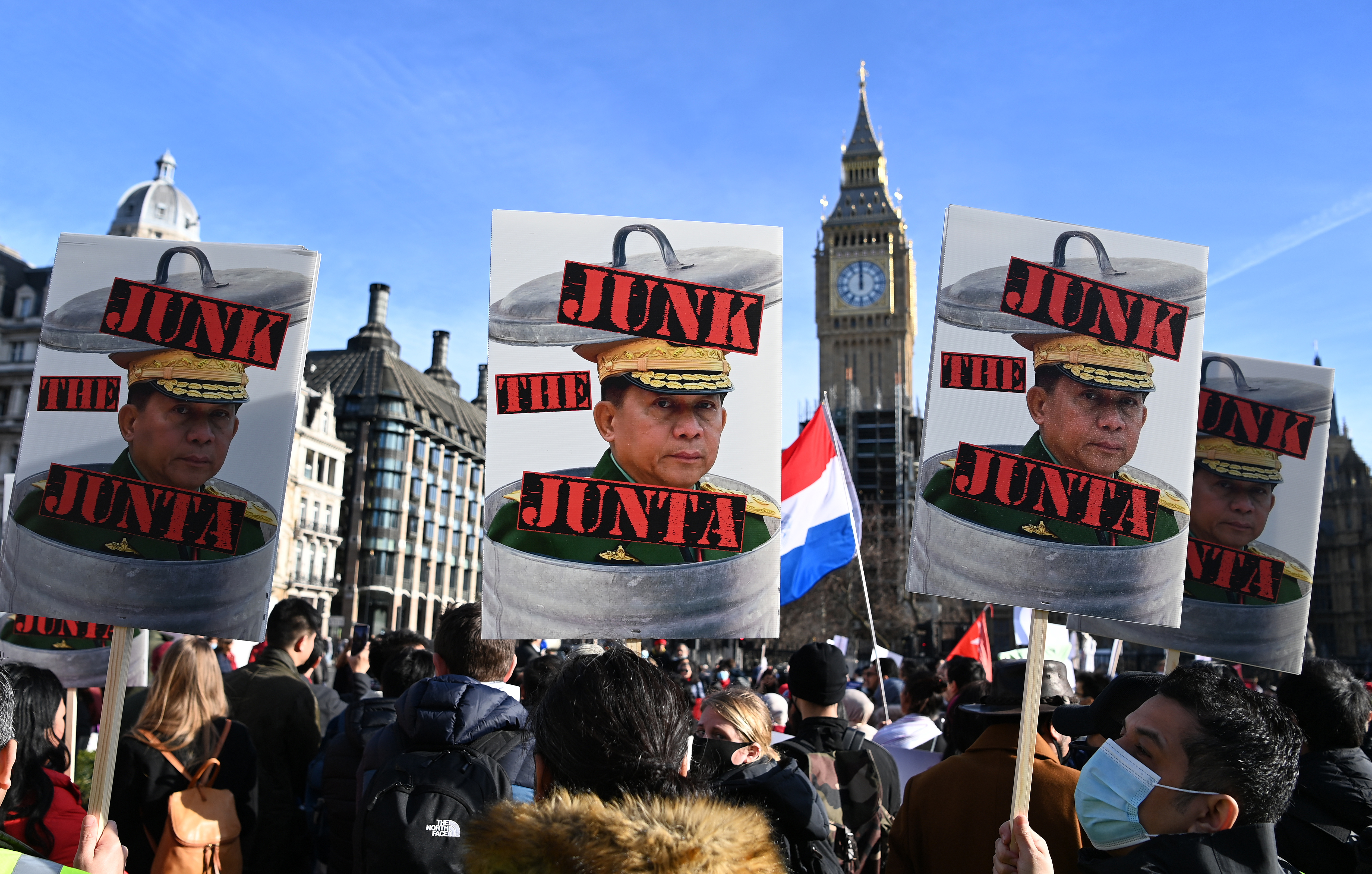 Protesters supporting Myanmar's anti-coup movement standing in front of Big Ben on a sunny day in London hold placards reading 'Junk the Junta'