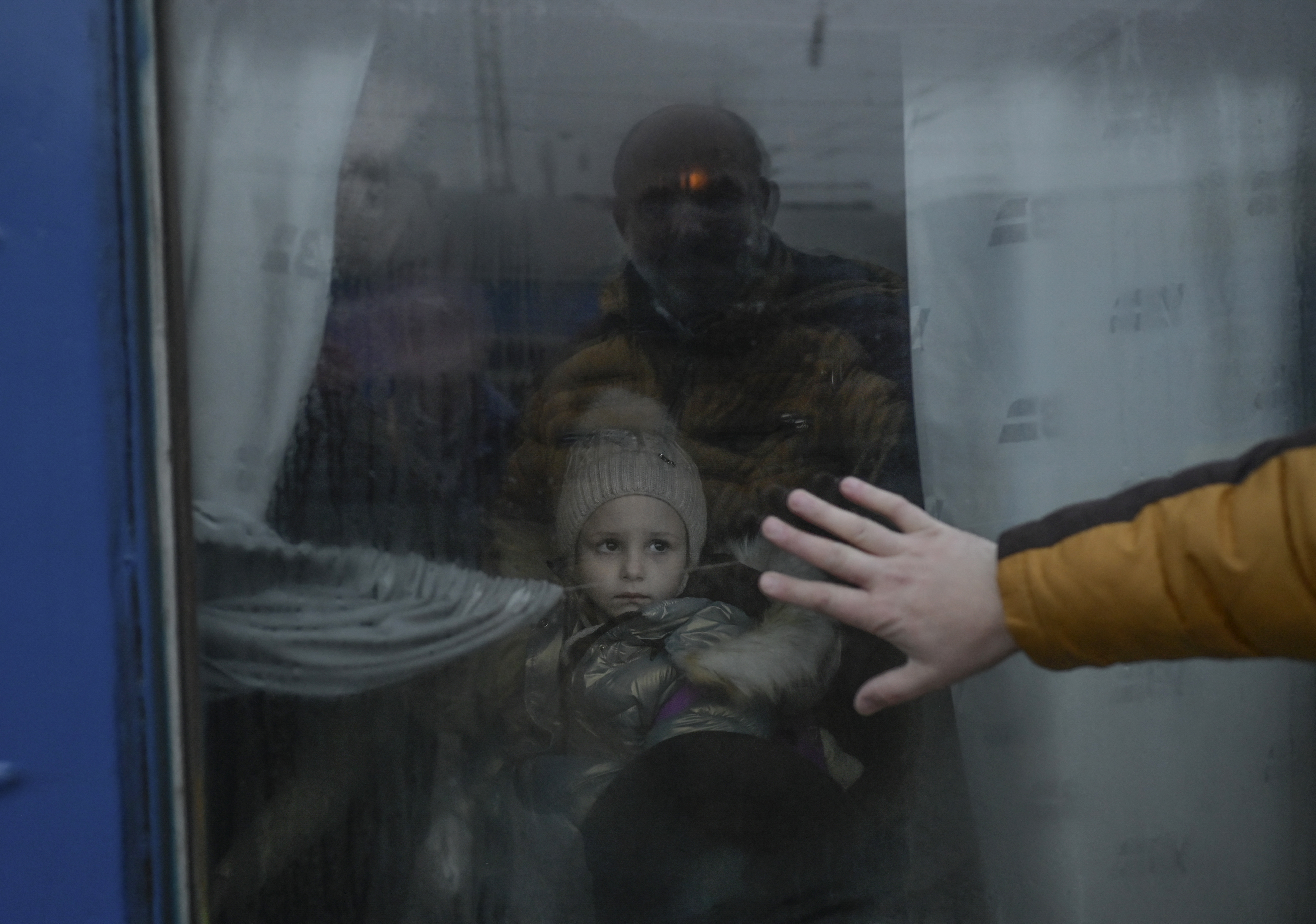 A father puts his hand on the window as he says goodbye to his daughter in front of an evacuation train at the central train station in Odessa