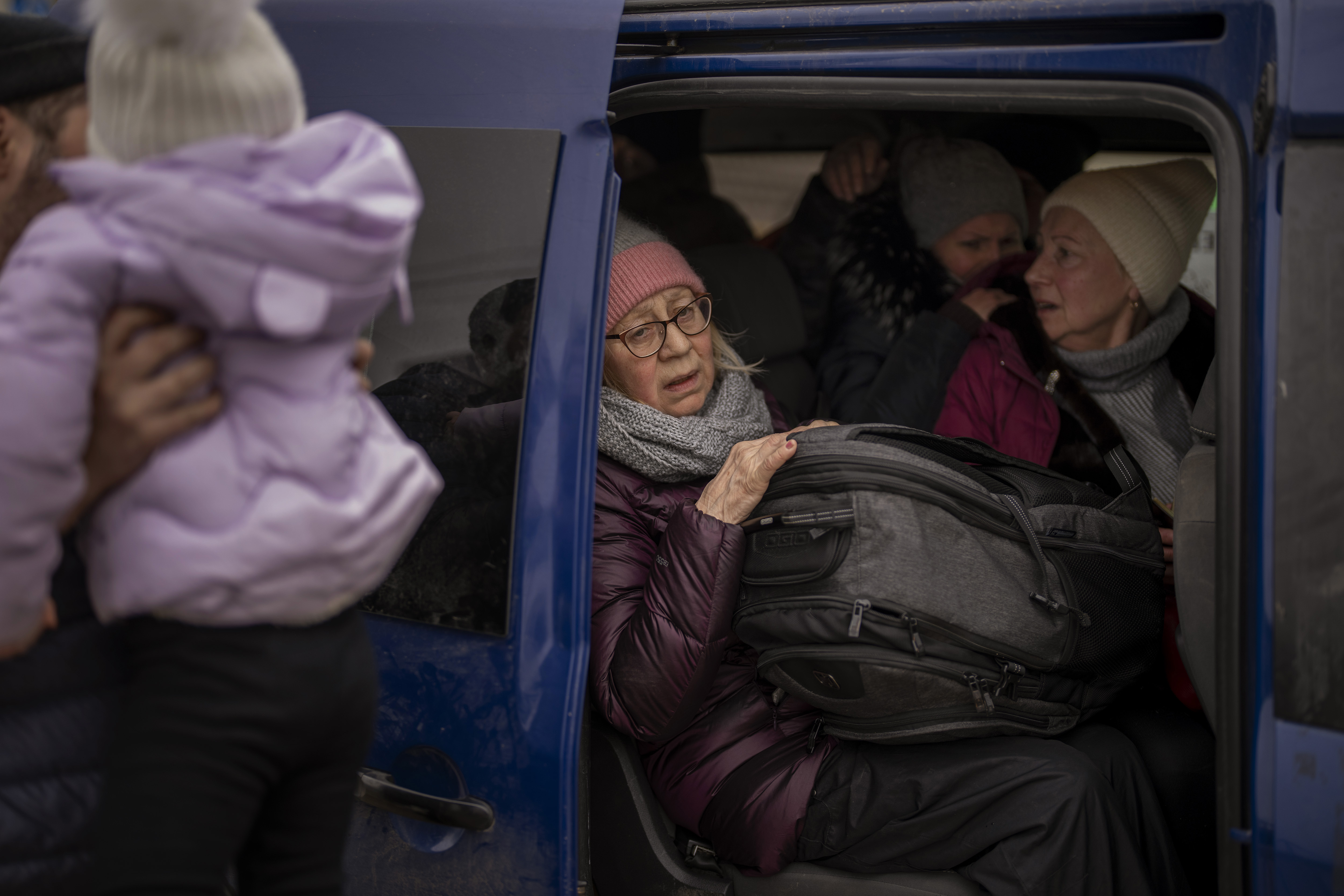 Ukrainian women sit inside a van as artillery echoes nearby, as people flee Irpin on the outskirts of Kyiv
