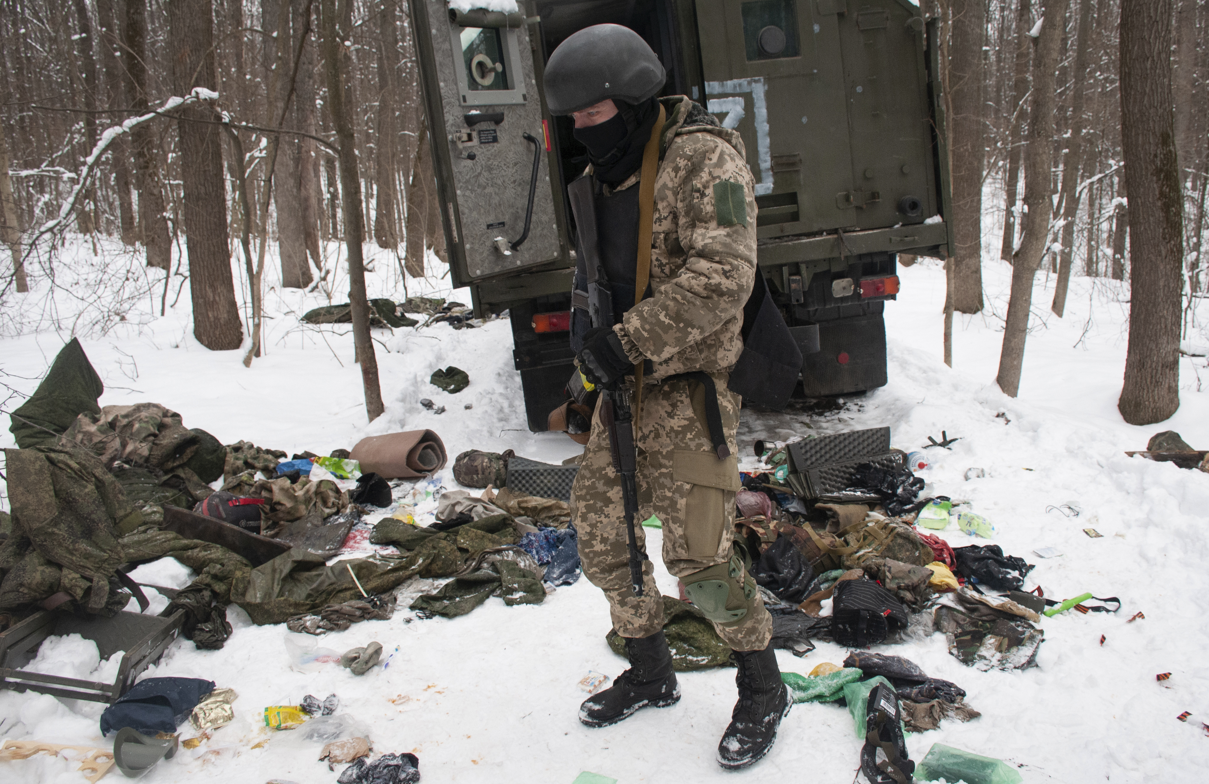 A volunteer of the Ukrainian Territorial Defense Forces inspects a damaged military vehicle in the outskirts Kharkiv