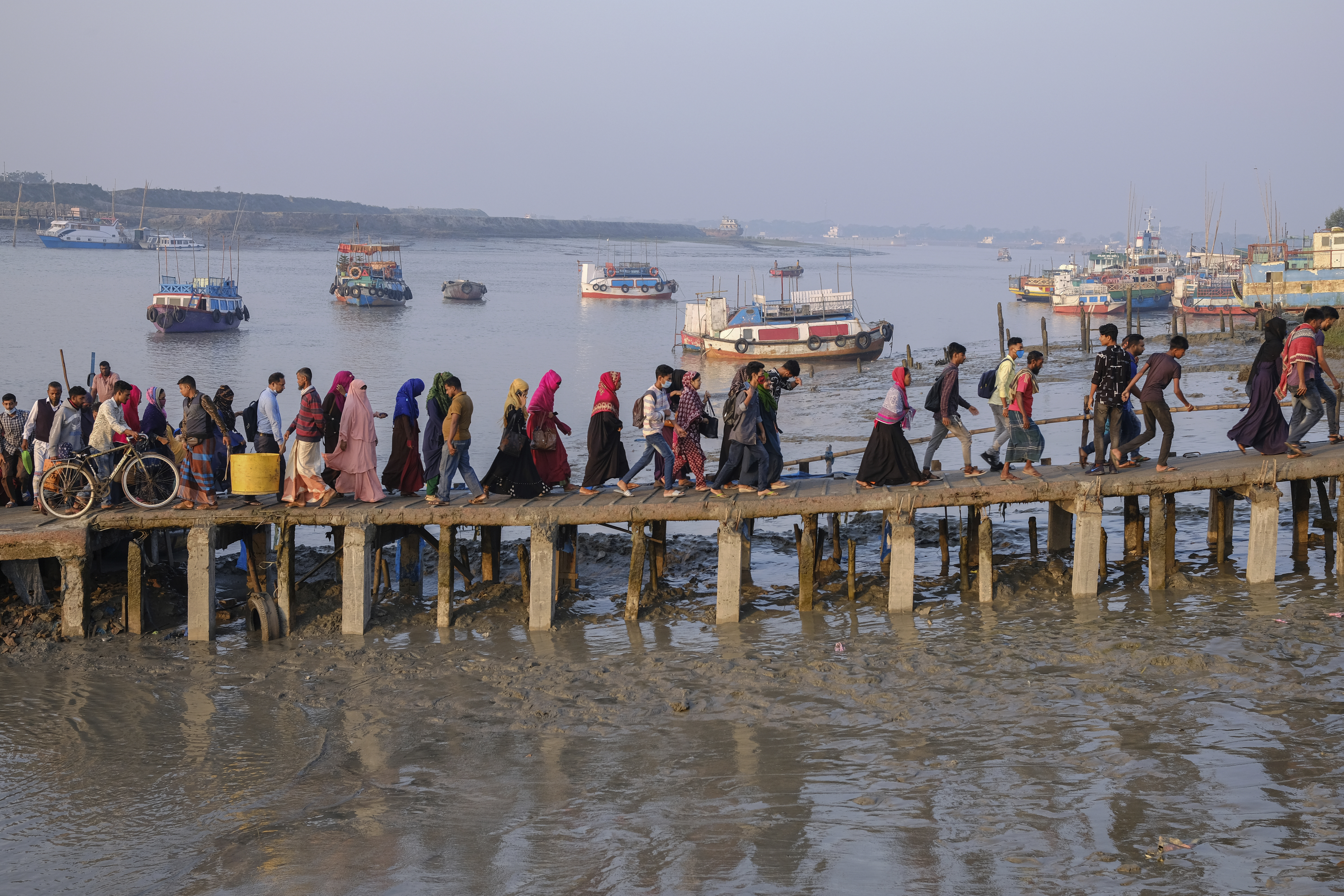 Workers walk to work at an export processing zone early in the morning after crossing the Mongla river in Mongla