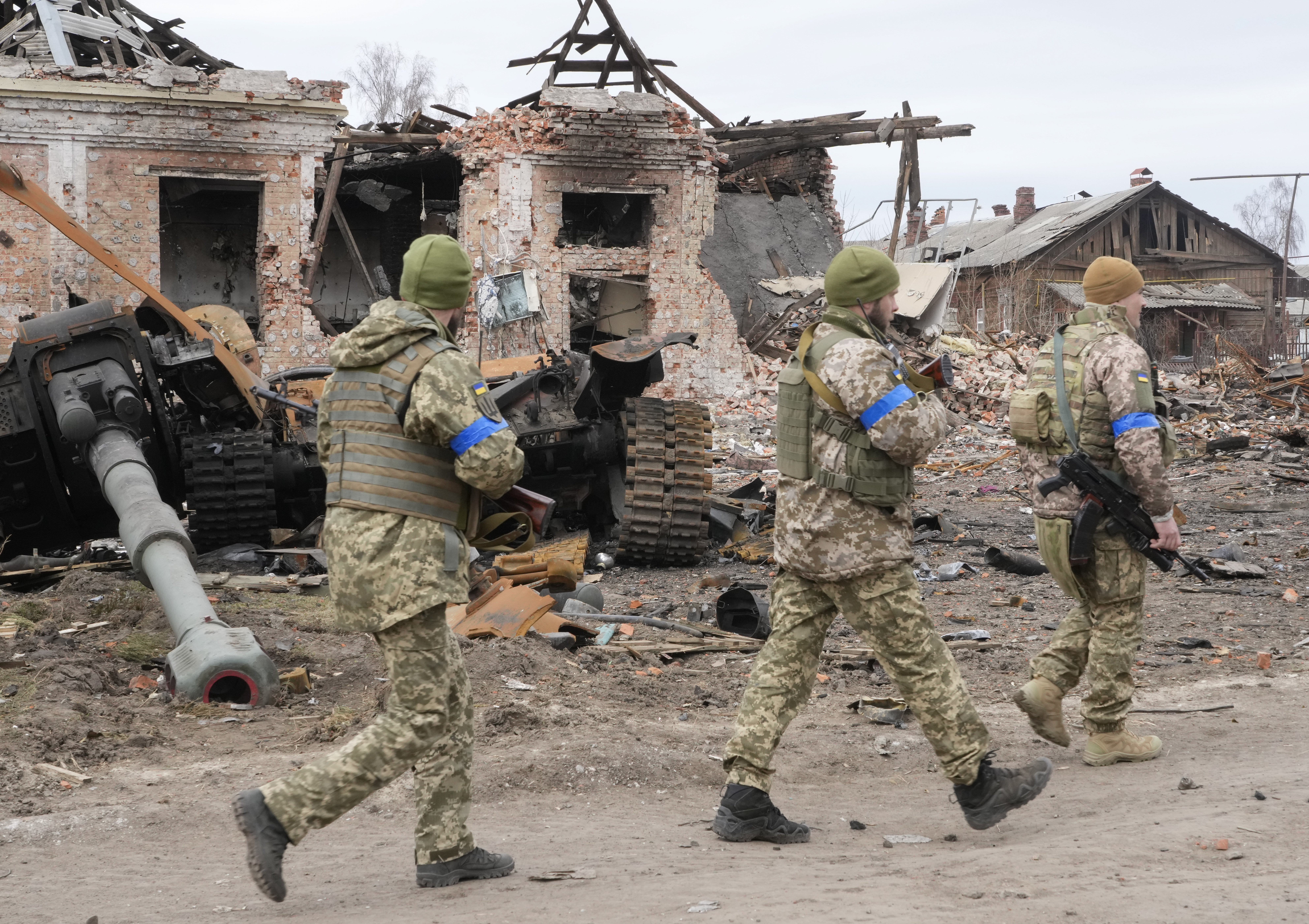 Ukrainian soldiers pass by a damaged Russian tank in the town of Trostsyanets, some 400km (250 miles) east of capital Kyiv, Ukraine, Monday, March 28, 2022. The more than month-old war has killed thousands and driven more than 10 million Ukrainians from their homes including almost 4 million from their country. (AP Photo/Efrem Lukatsky)