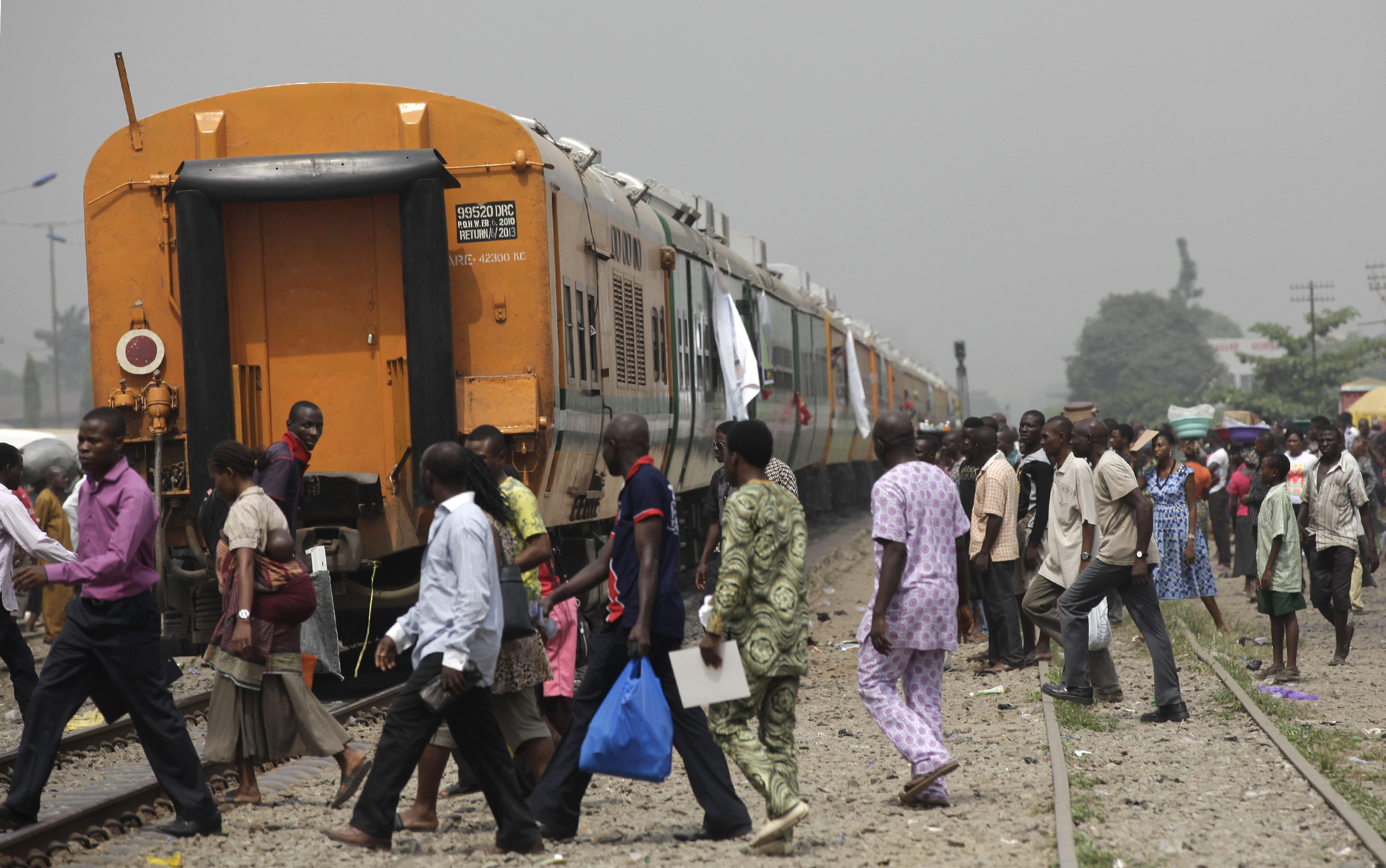 People cross the tracks as they wait for the train to move off as part of a newly inaugurated train service to Kano, Nigeria, in Lagos