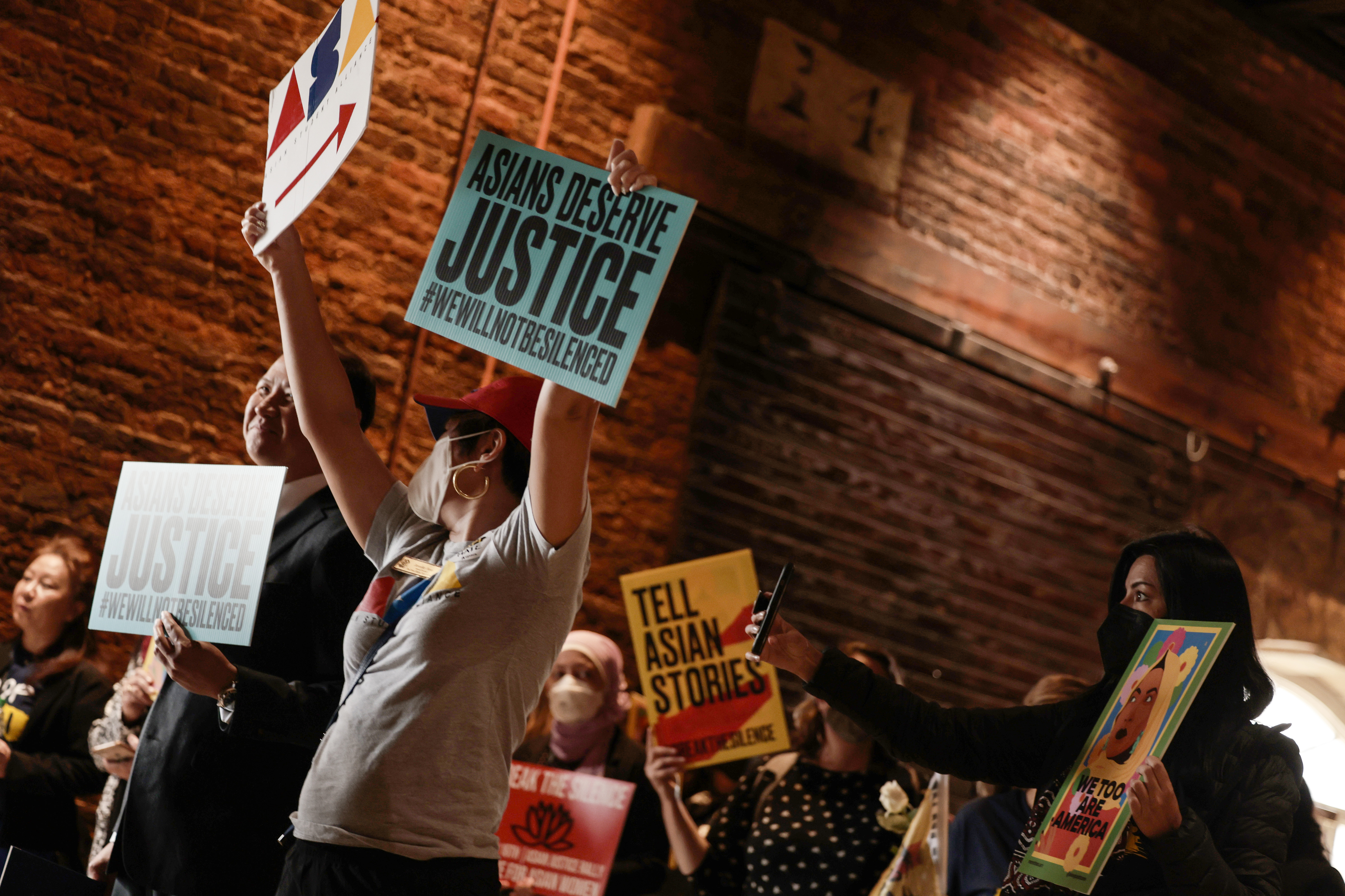 Demonstrators hold up signs as they arrive for the start of “The Asian Justice Rally – Break the Silence