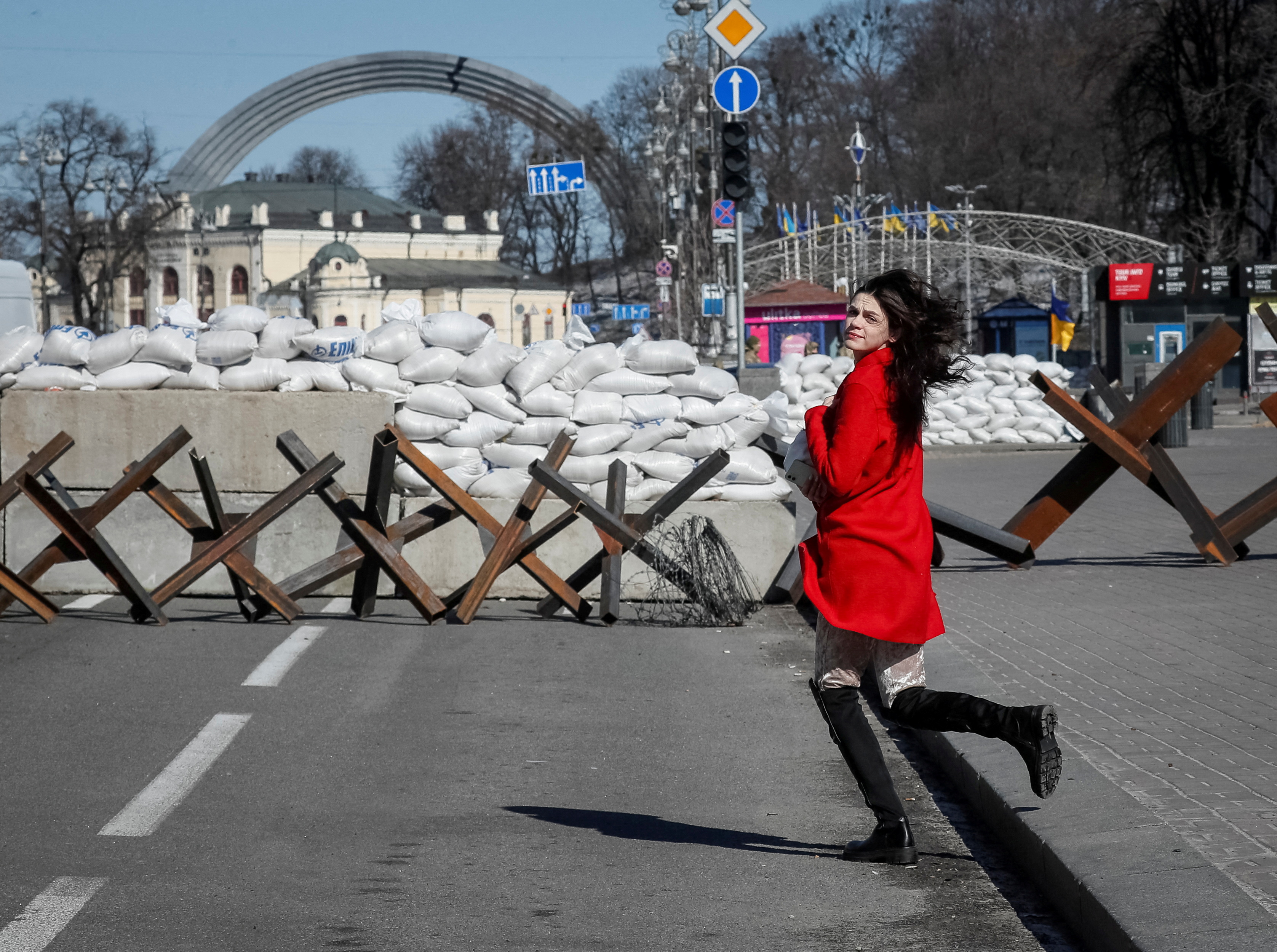 A woman runs across the street next to an anti-tank constructions in central Kyiv.