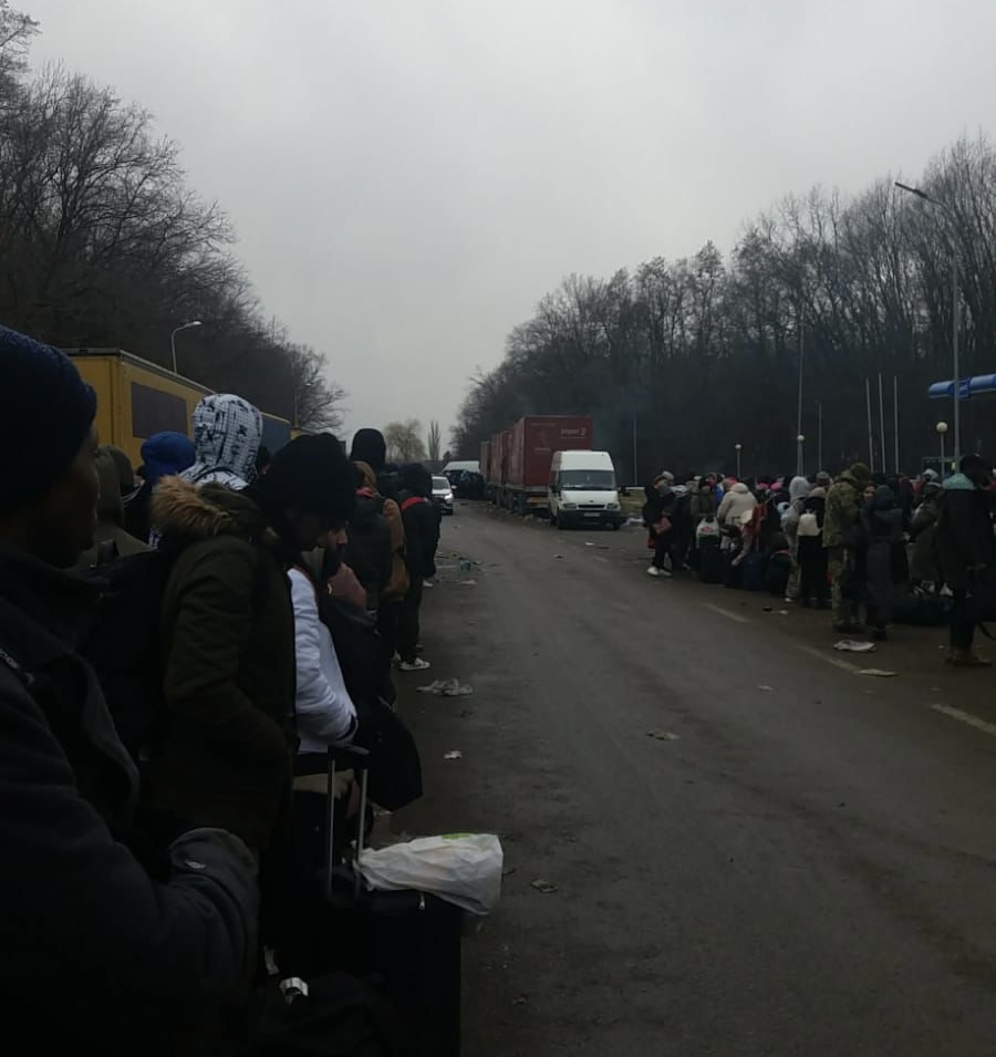 Queues of people standing on a road.