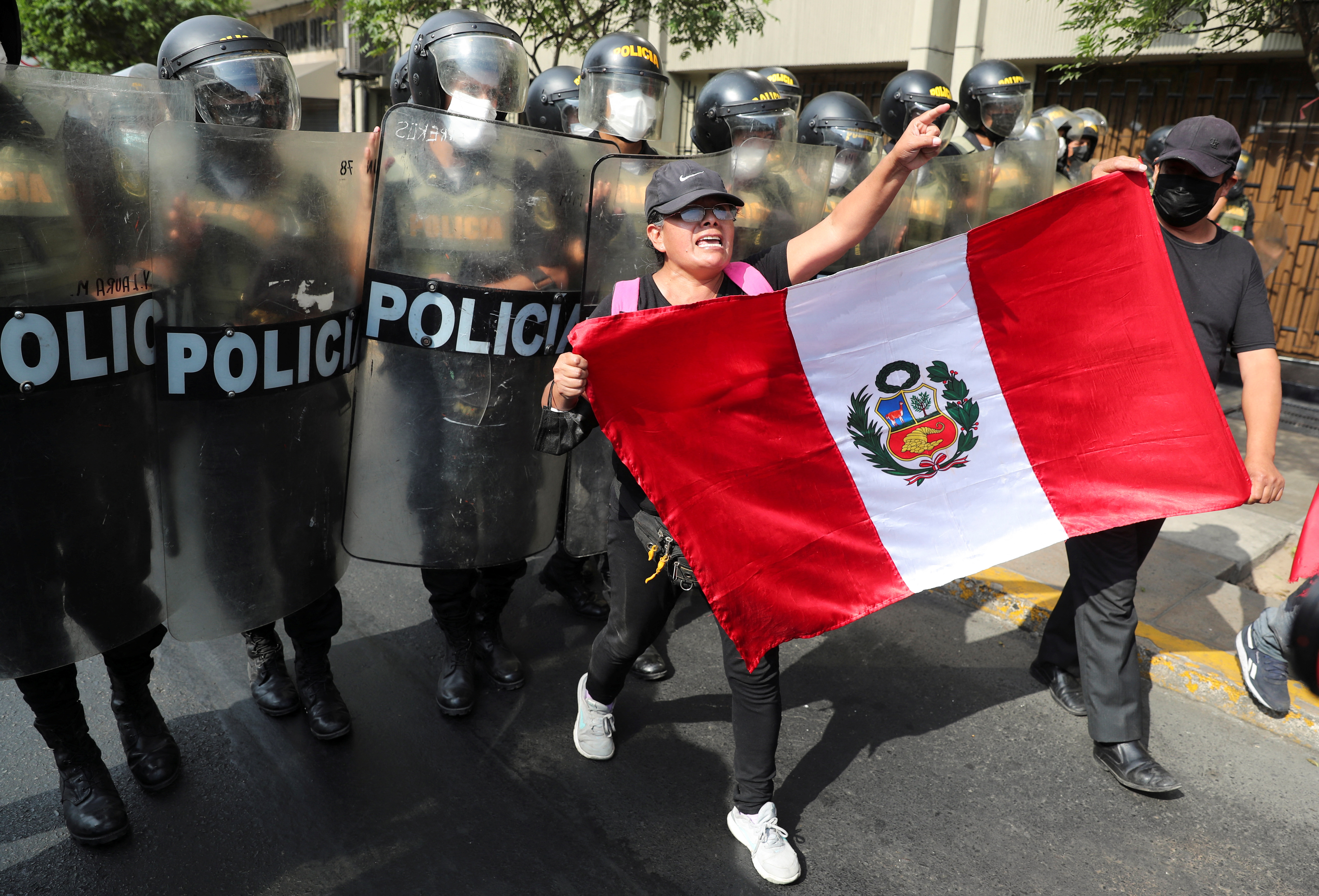A demonstrator with a Peruvian flag marches in front of riot police in Lima, Peru.