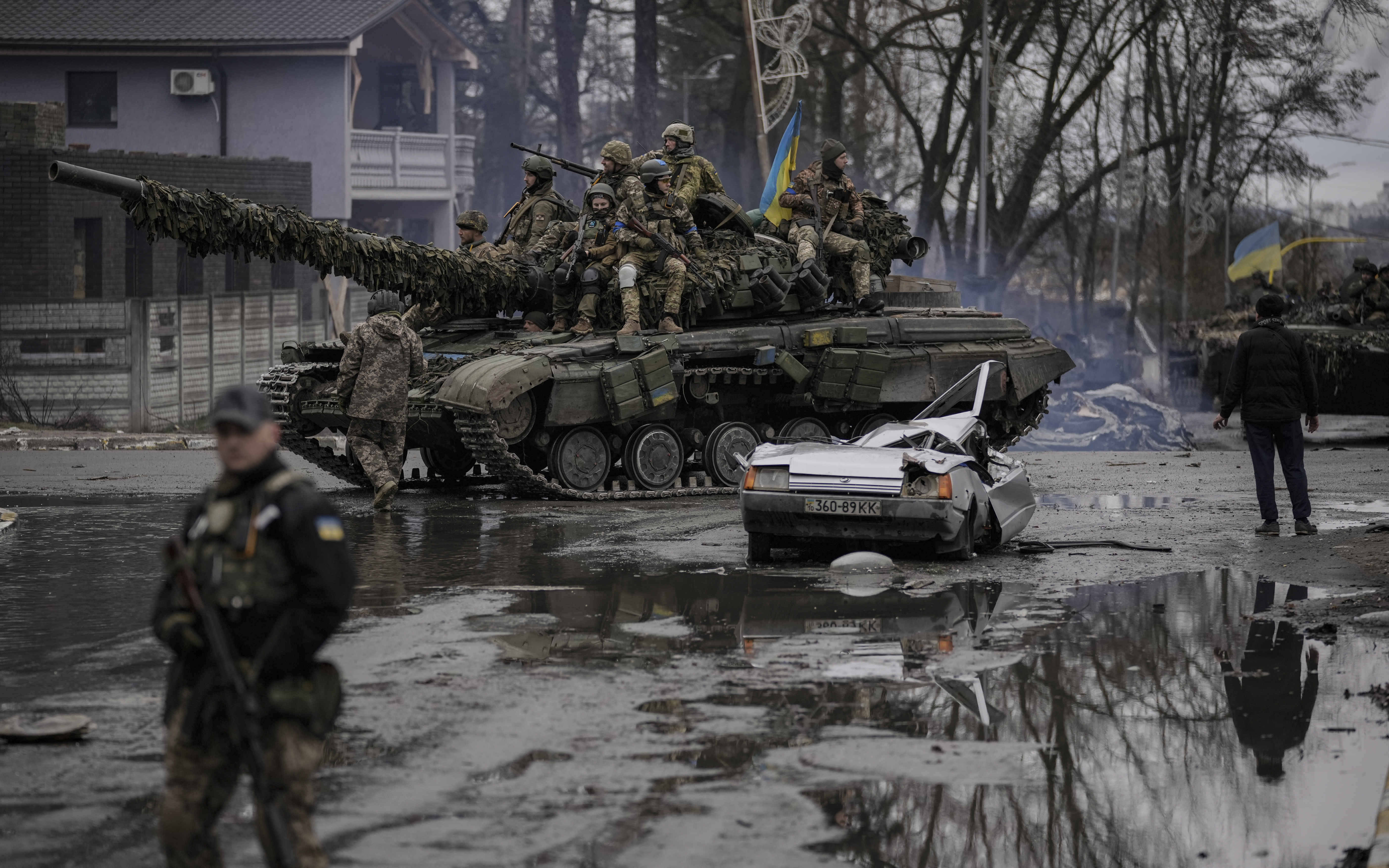 A man stands next to a civilian vehicle that was destroyed during fighting between Ukrainian and Russian forces that still contains the dead body of the driver