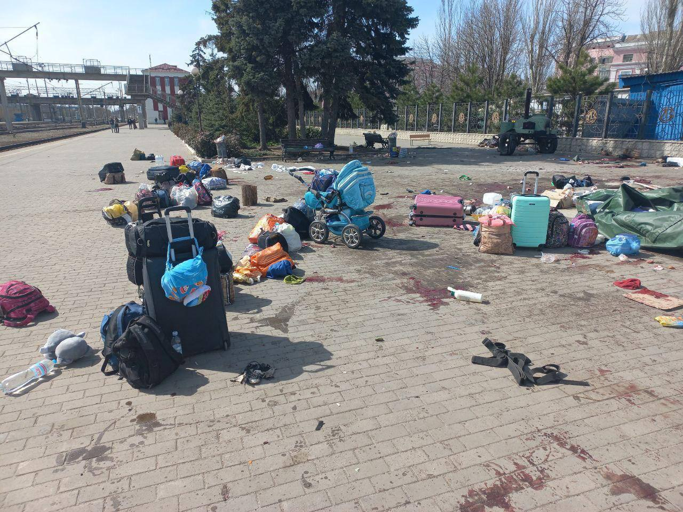 Blood stains are seen among bags and a baby carriage on a train station platform