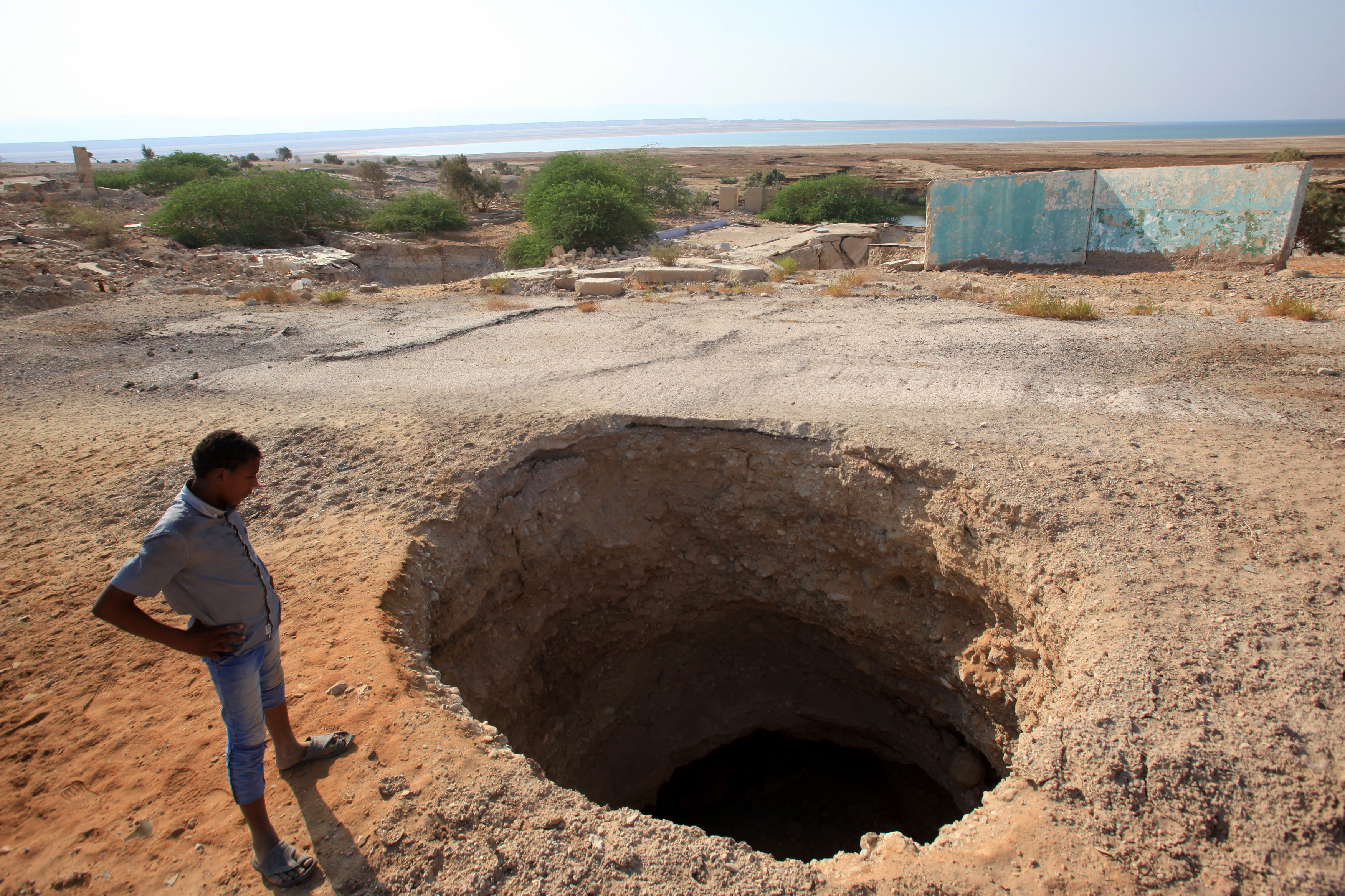 A Jordanian looks at a sinkhole on the Dead Sea shore near Haditha, Jordan