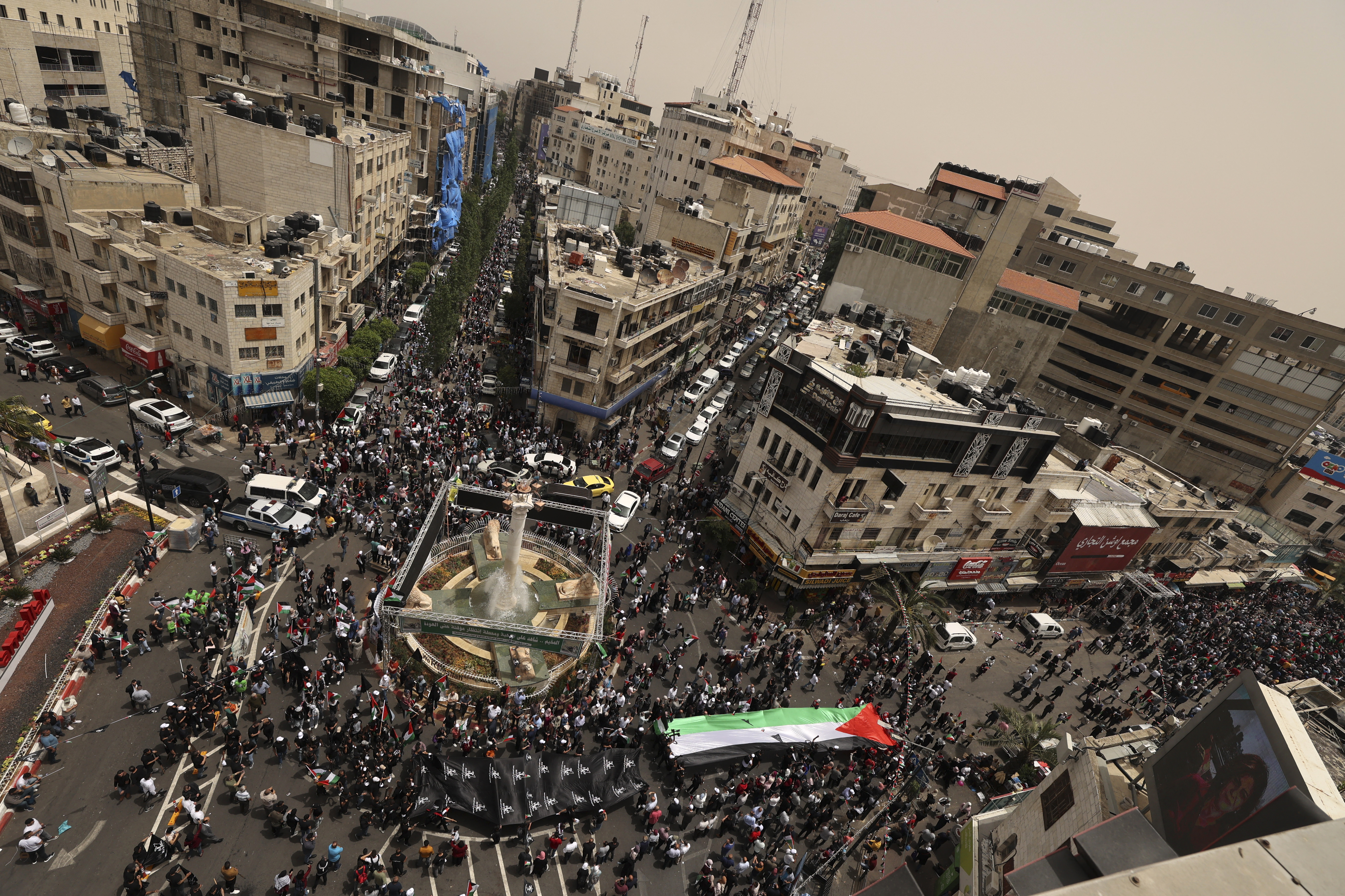 Palestinian wave national flags as they march in a rally marking the 74th anniversary of the "Nakba" or "catastrophe"