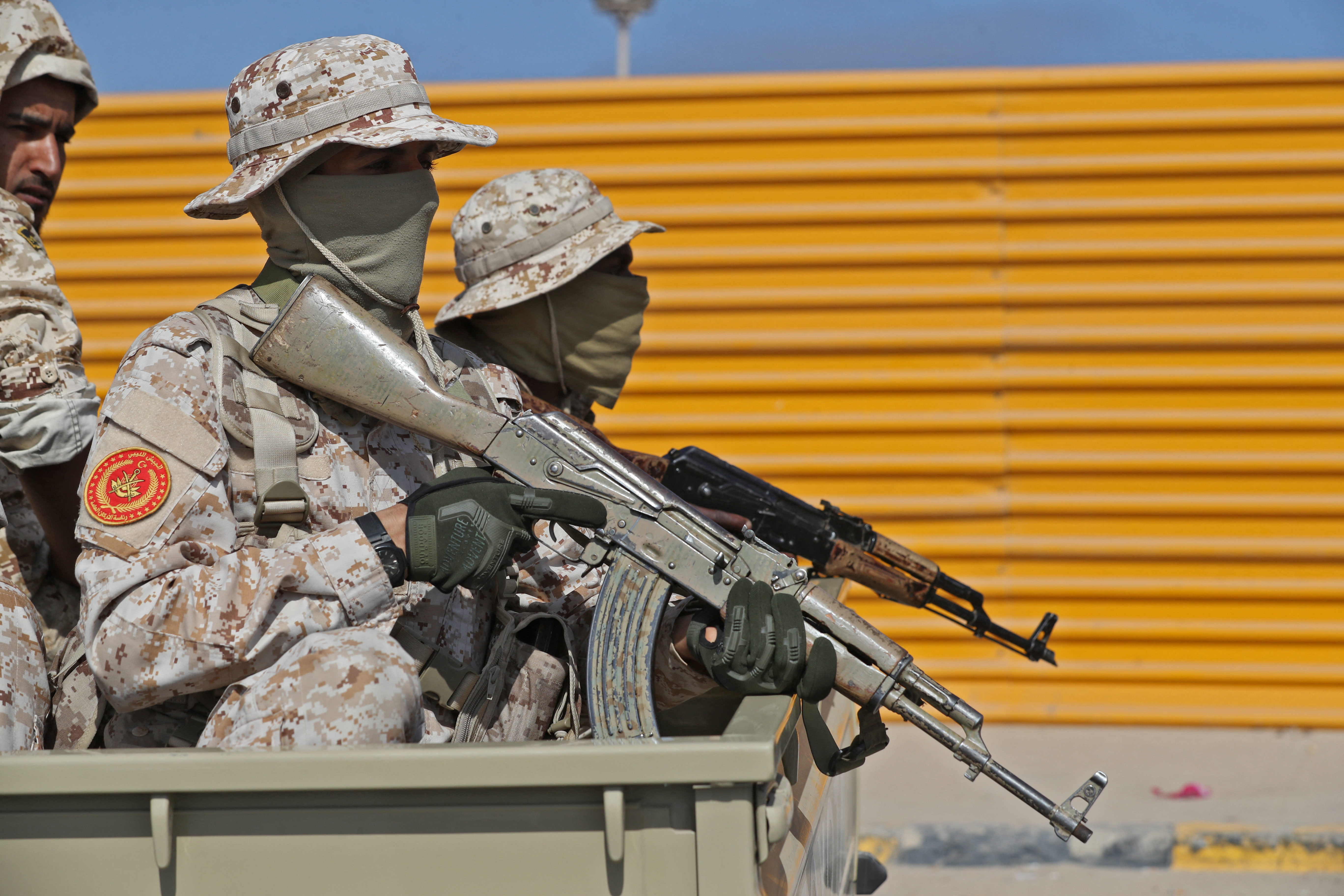 Fighters loyal to Libya's Tripoli-based Prime Minister Abdulhamid Dbeibah sit with their arms in the back of a pickup truck
