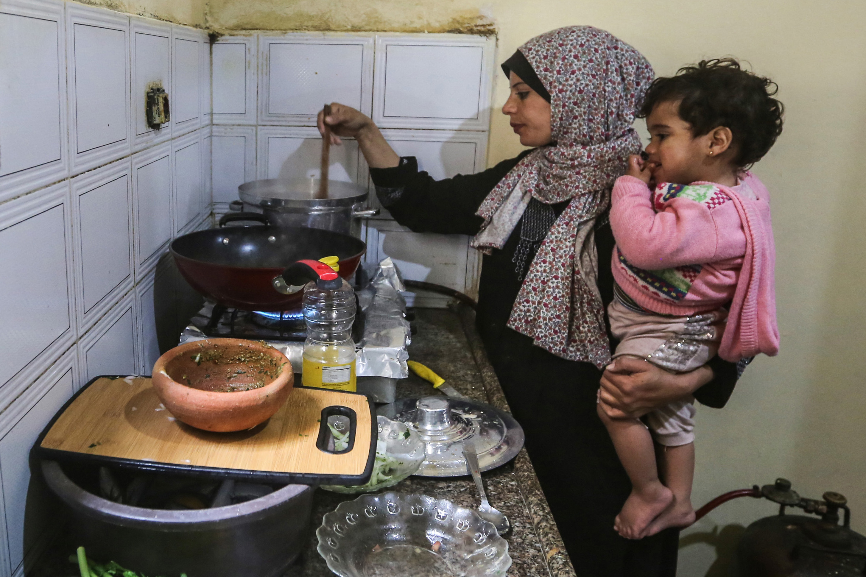 Madelyn holds Sandy in one arm as she stirs a pot on the stove