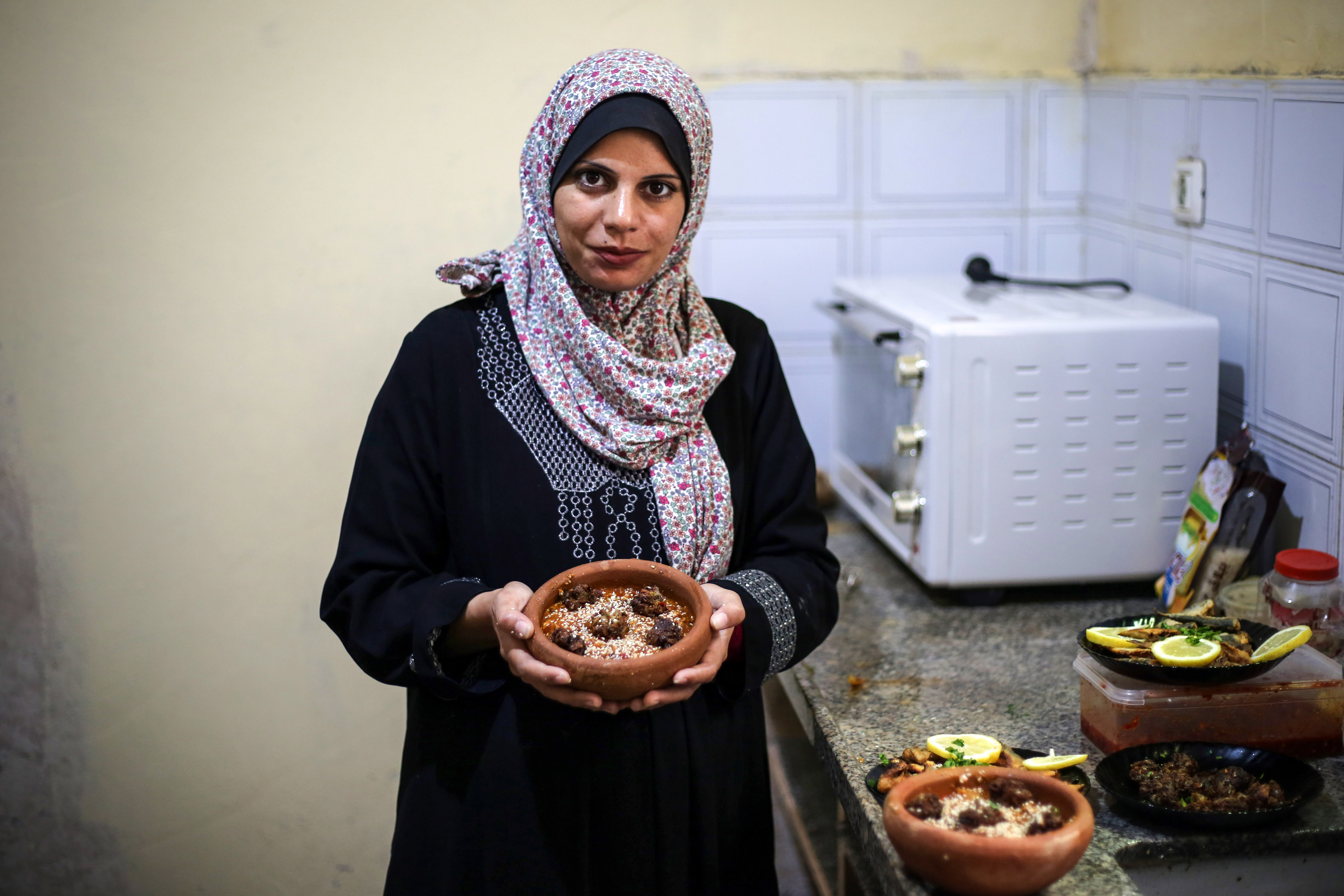 Madelyn holds a clay pot of fish kofta