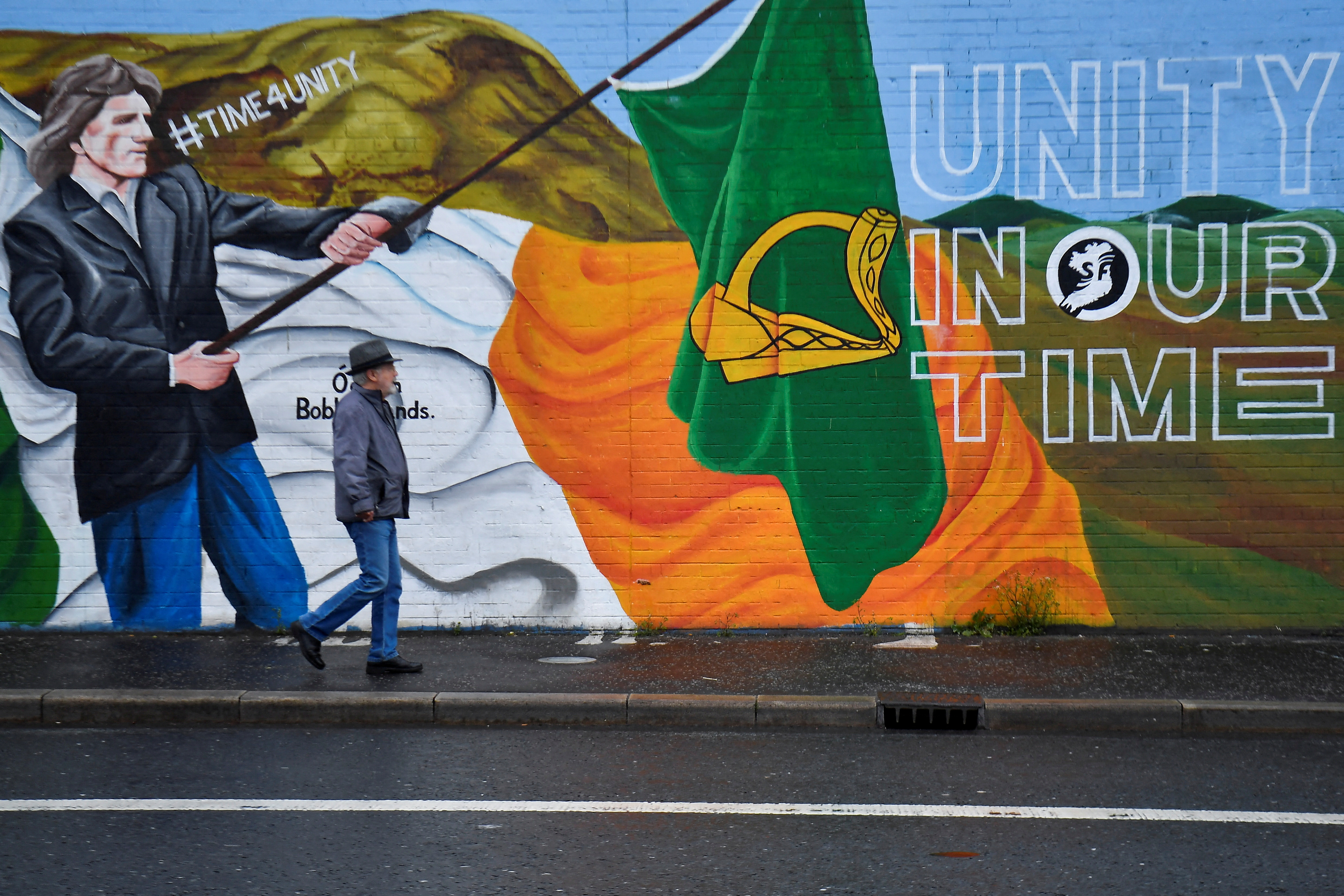 A man walks past a mural along the nationalist Falls Road, in Belfast