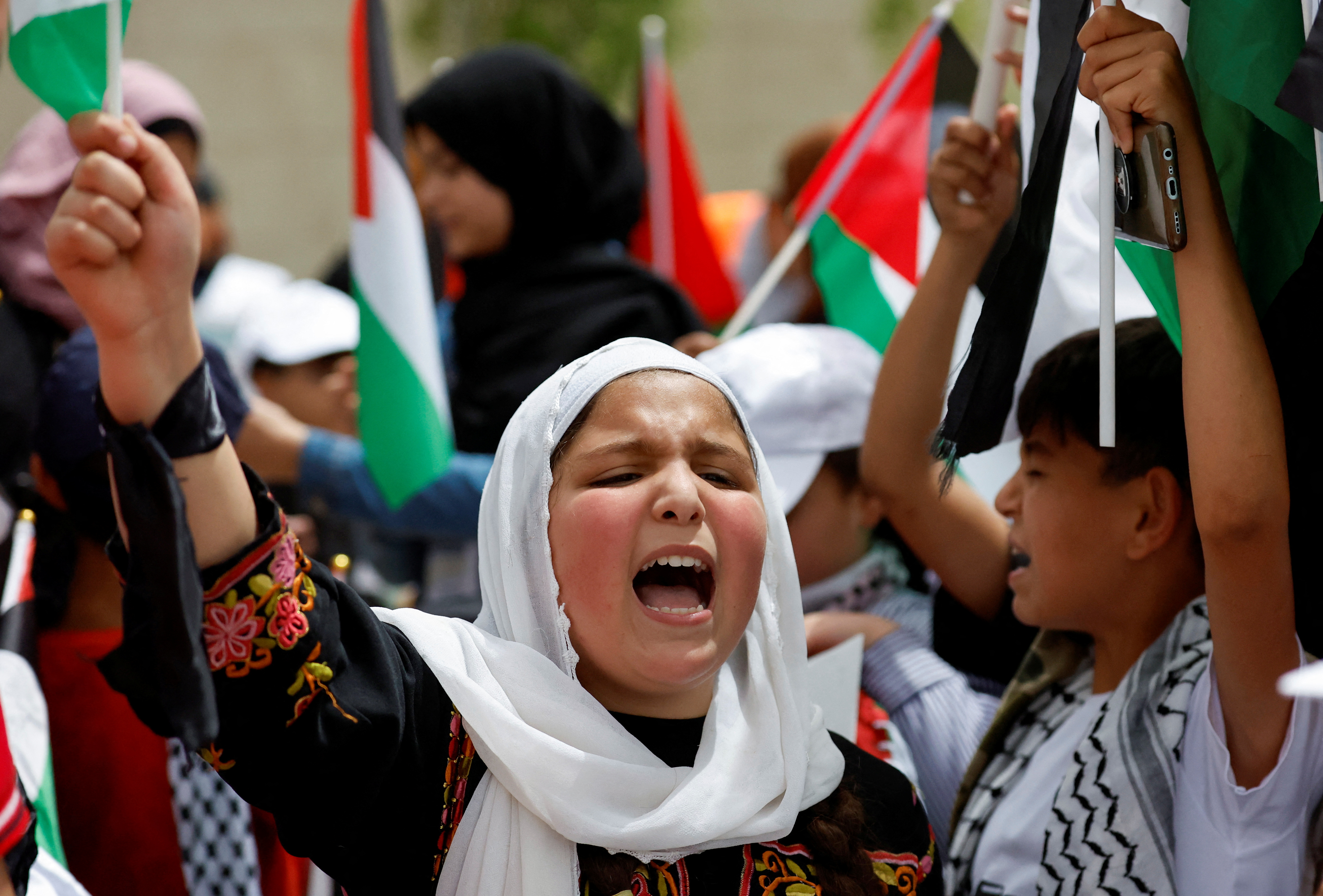 Palestinian wave national flags as they march in a rally marking the 74th anniversary of the "Nakba" or "catastrophe"